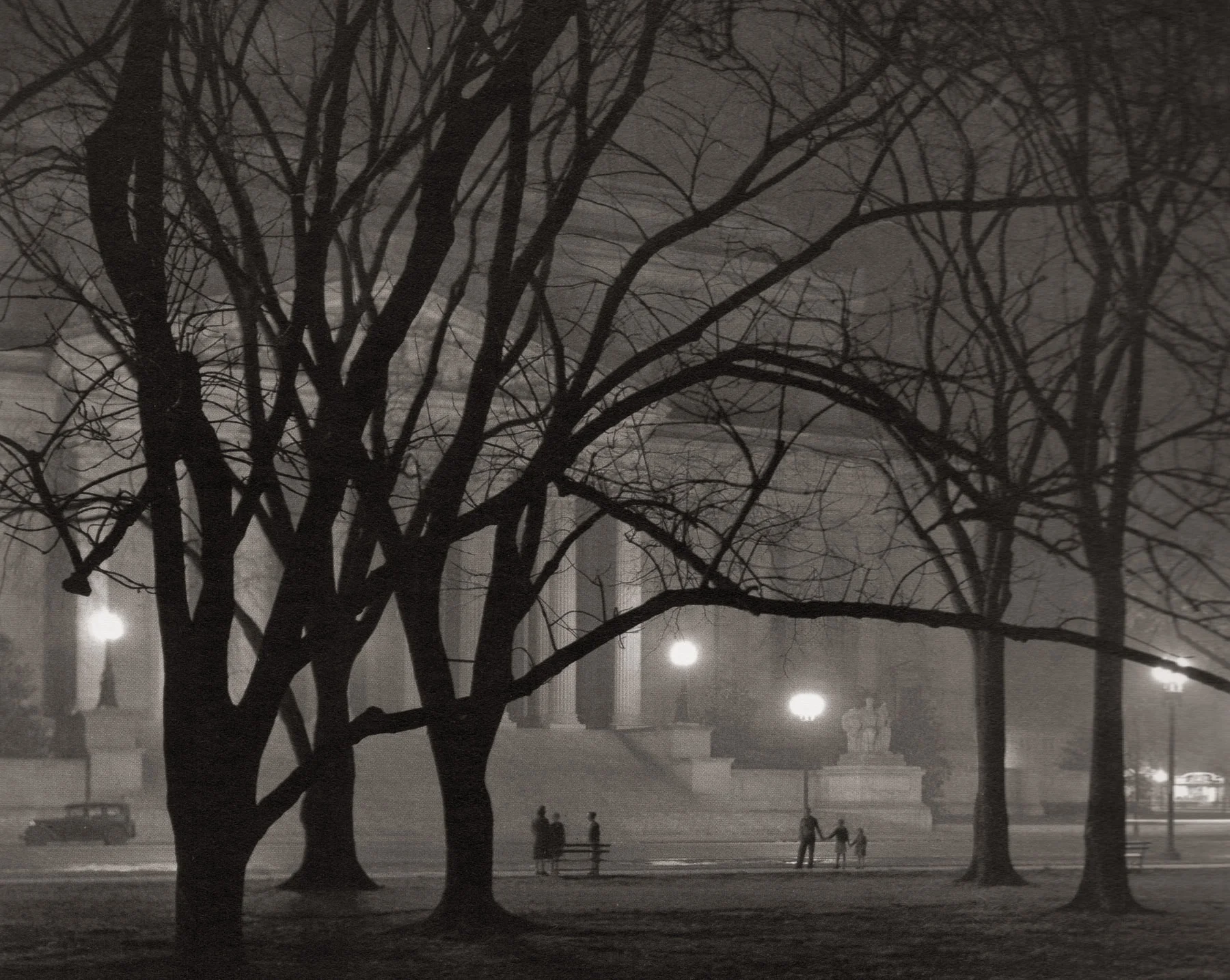 “National Archives.” The National Archives building had just been completed in 1935 when Wentzel made this image on a foggy night. Two groups of people illustrate the grand scale of the building, and the looming presence of the bare trees in the foreground add an air of mystery to the image.