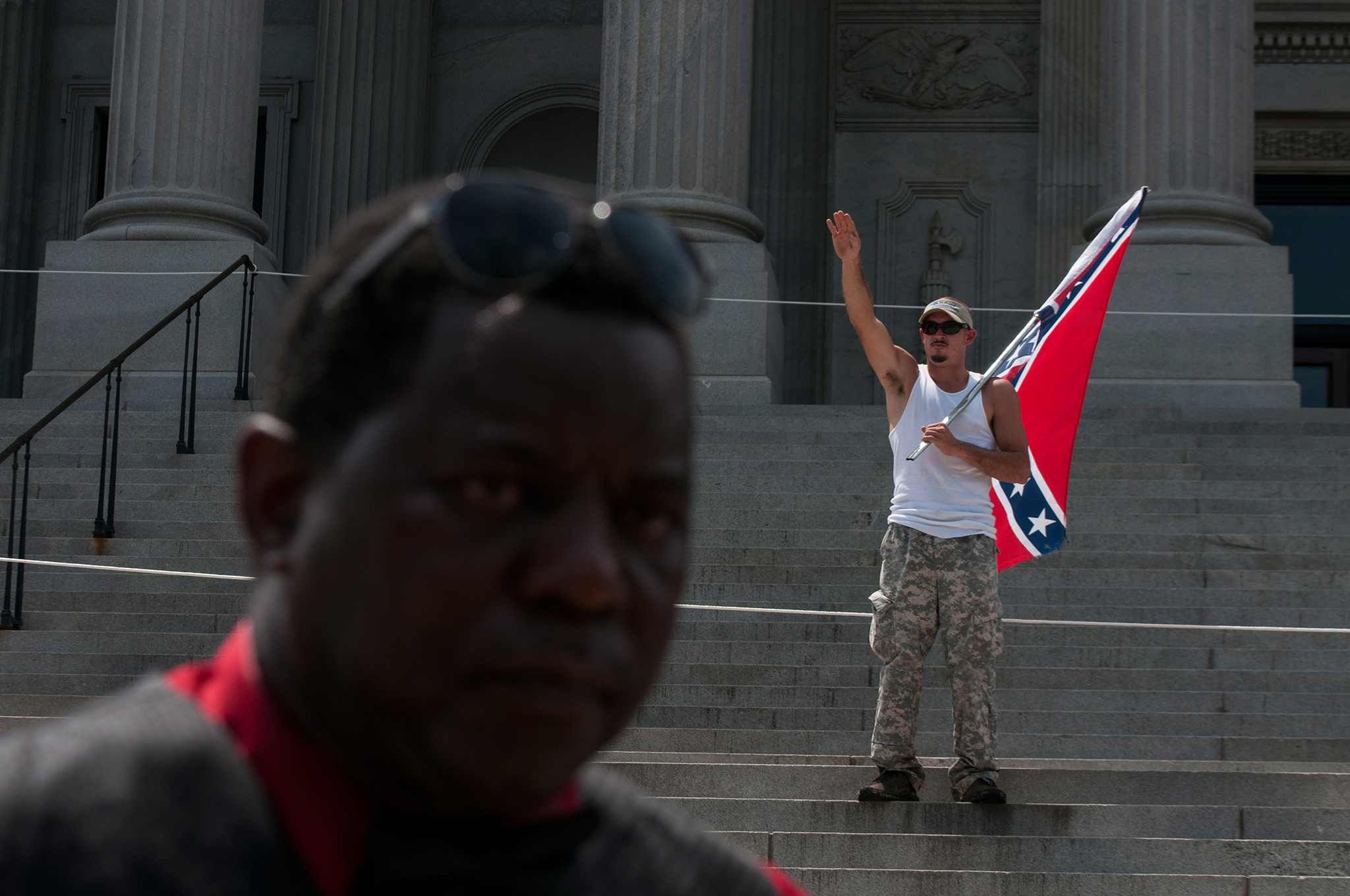 A Ku Klux Klan supporter protests the removal of the Confederate flag from the State House in Columbia, South Carolina as one of the leaders of the New Black Panthers Party delivers a speech during a counter protest. The KKK and the Black Panthers held competing rallies at the South Carolina capitol building, resulting in clashes between protesters.