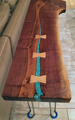 You will never find another one like it. This beautiful console/sofa table will give your entryway a wow factor, or place it behind a sofa for a gorgeous living room piece. Three maple bowtie joints and turquoise inlays add contrast to the rich, dark black walnut and adds unique character for this one-of-a-kind piece. Add the beautiful table is sure to turn many heads and will make a wonderful addition to any modern home. This black walnut live edge console/sofa table is 5' long X 14" wide X 30” tall and 2" thick with four mid-century modern hairpin legs. The table has five coats of a satin poly blend, and has a glass smooth finish....$500.00 SOLD