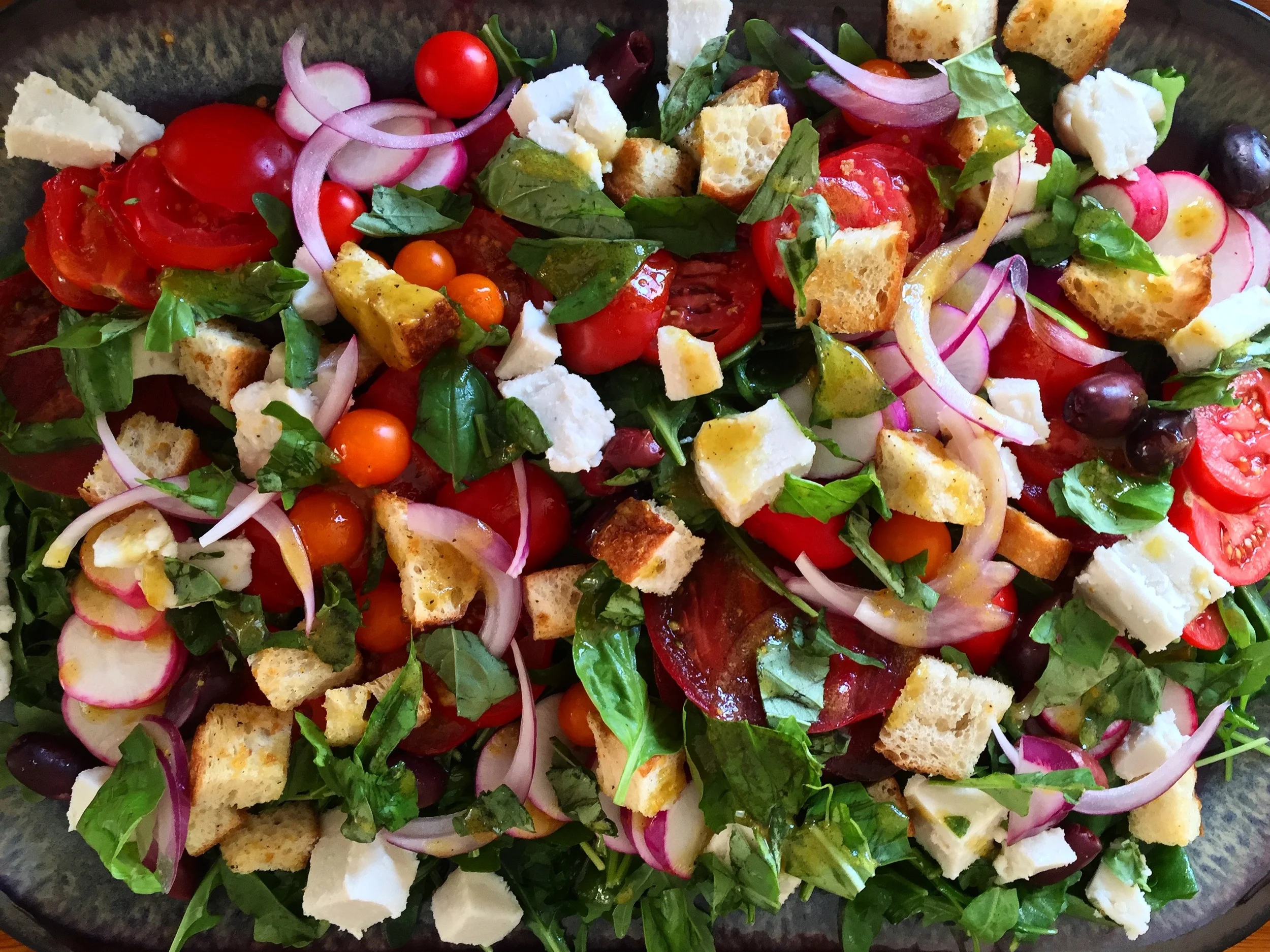 Heirloom tomatoes, 'mozzarella' (made with cashew), radishes, kalamata olives with homemade croutons and basil dressing on a bed of arugula.