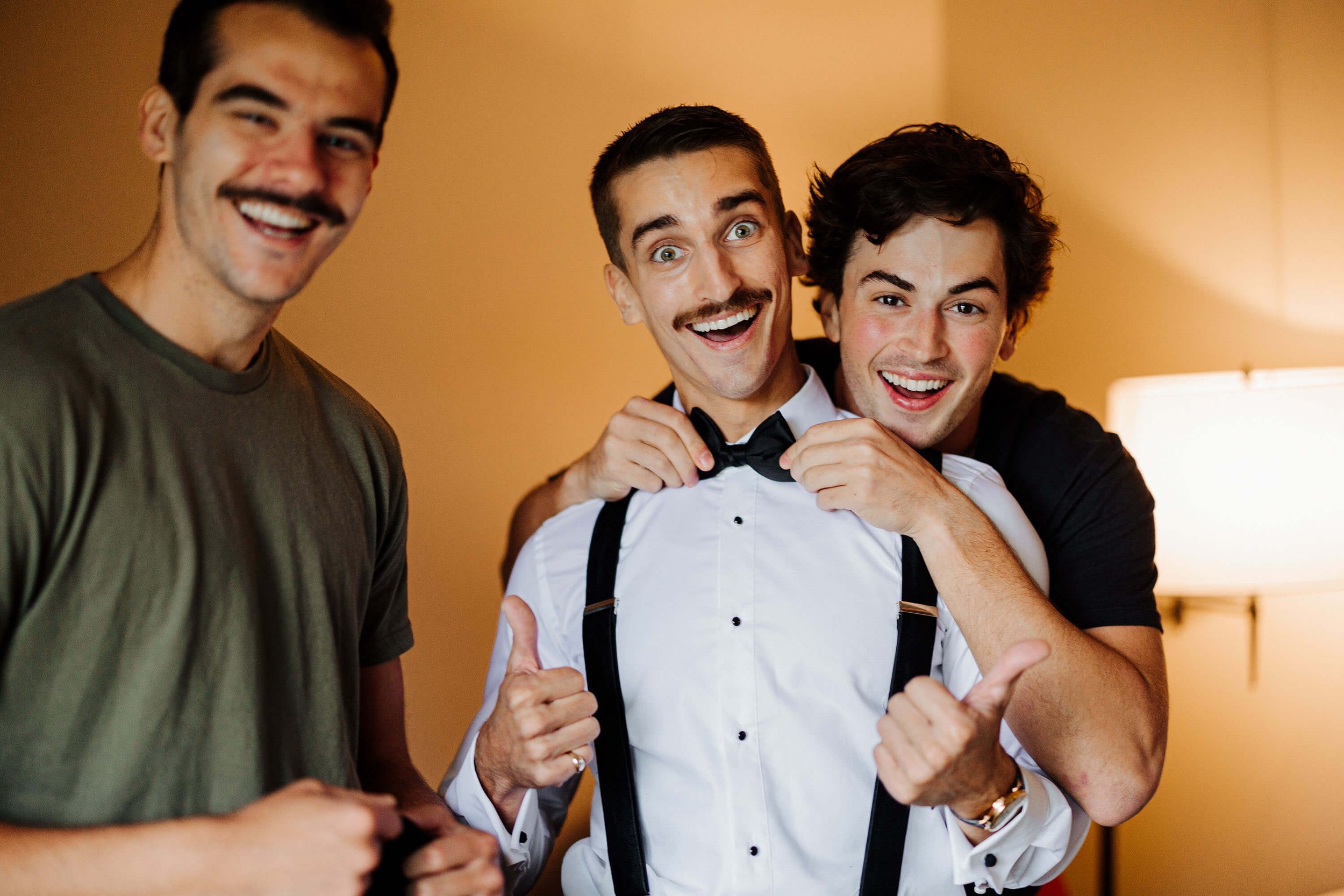The Highlands wedding photographer Harbor Springs Michigan candid groom laughing with groomsmen bow tie prep, luxury Northern Michigan wedding photography