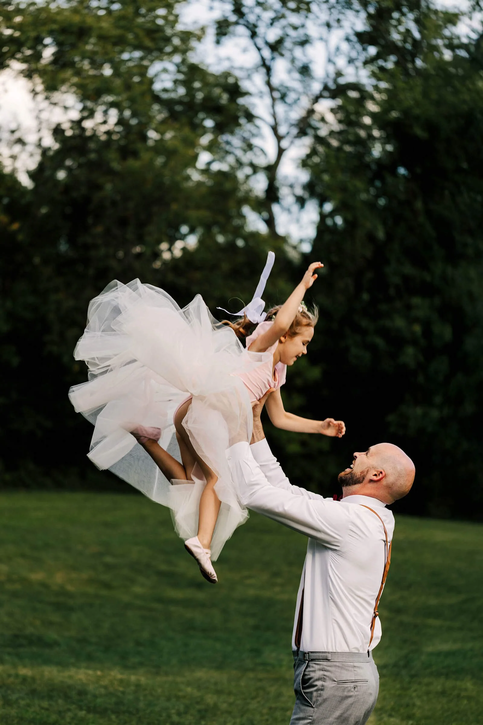 GAUPERphoto Detroit Michigan backyard wedding photographer candid groomsman tossing flower girl at golden hour, best unposed wedding moment
