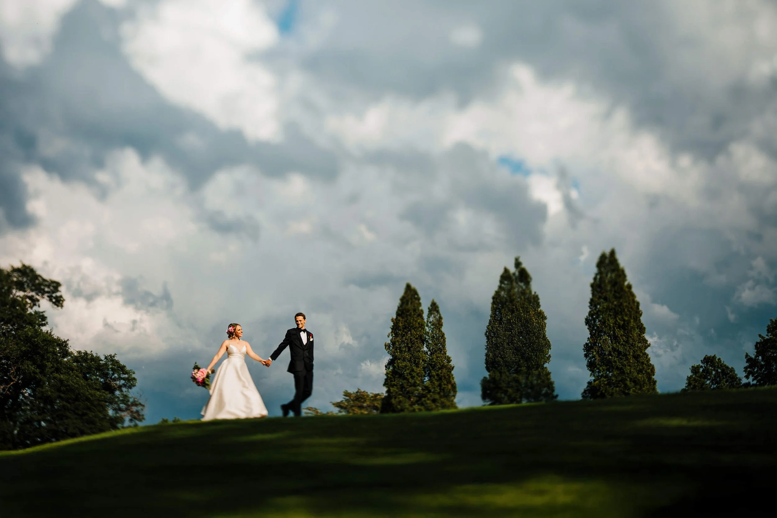 Carriage Greens Country Club wedding photographer Darien Illinois candid bride leading packed dance floor with arms raised and guests all hands up, top luxury Illinois wedding photography
