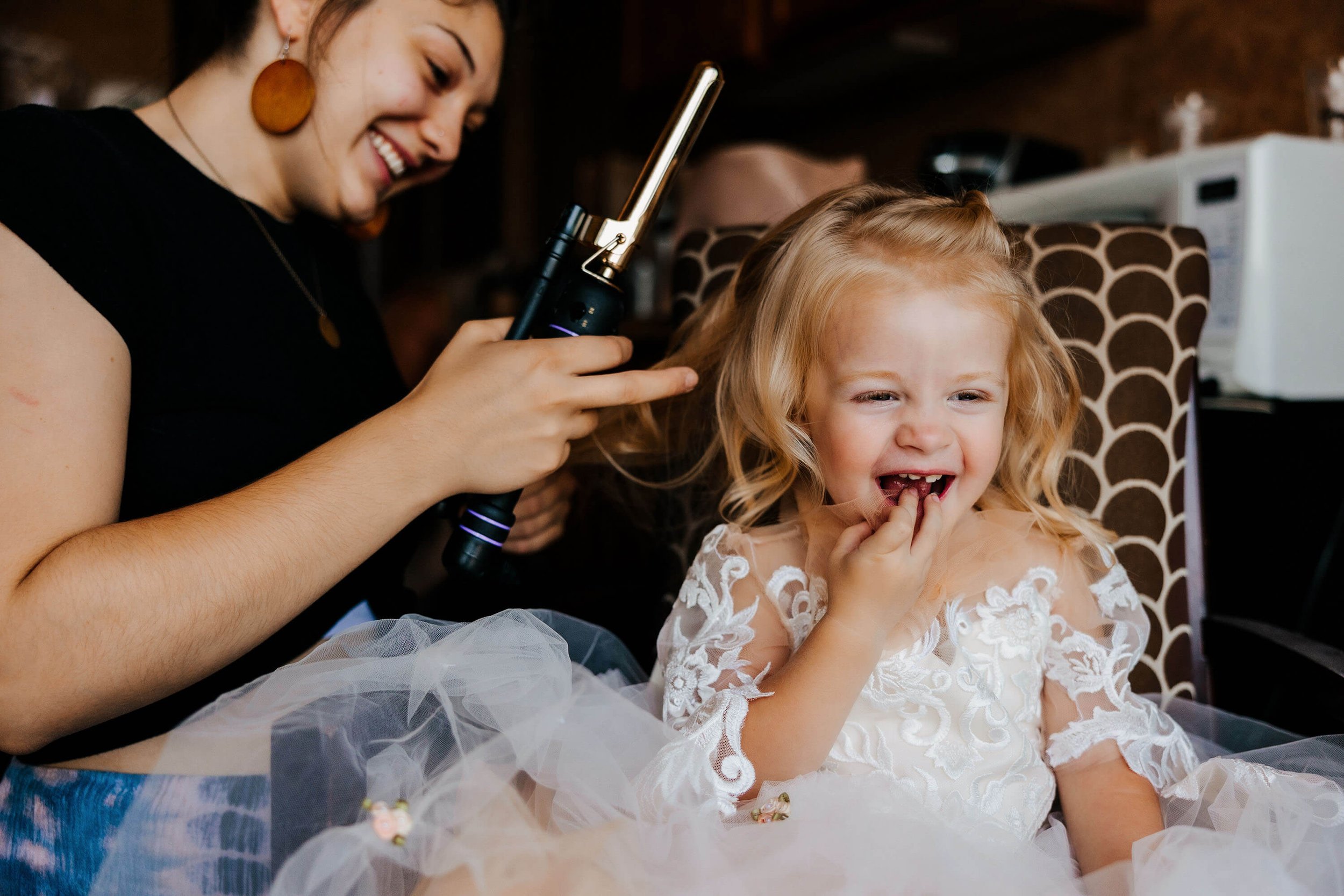 Muskegon Michigan wedding photographer candid flower girl laughing during hair styling getting ready, Shoreline Inn best West Michigan wedding