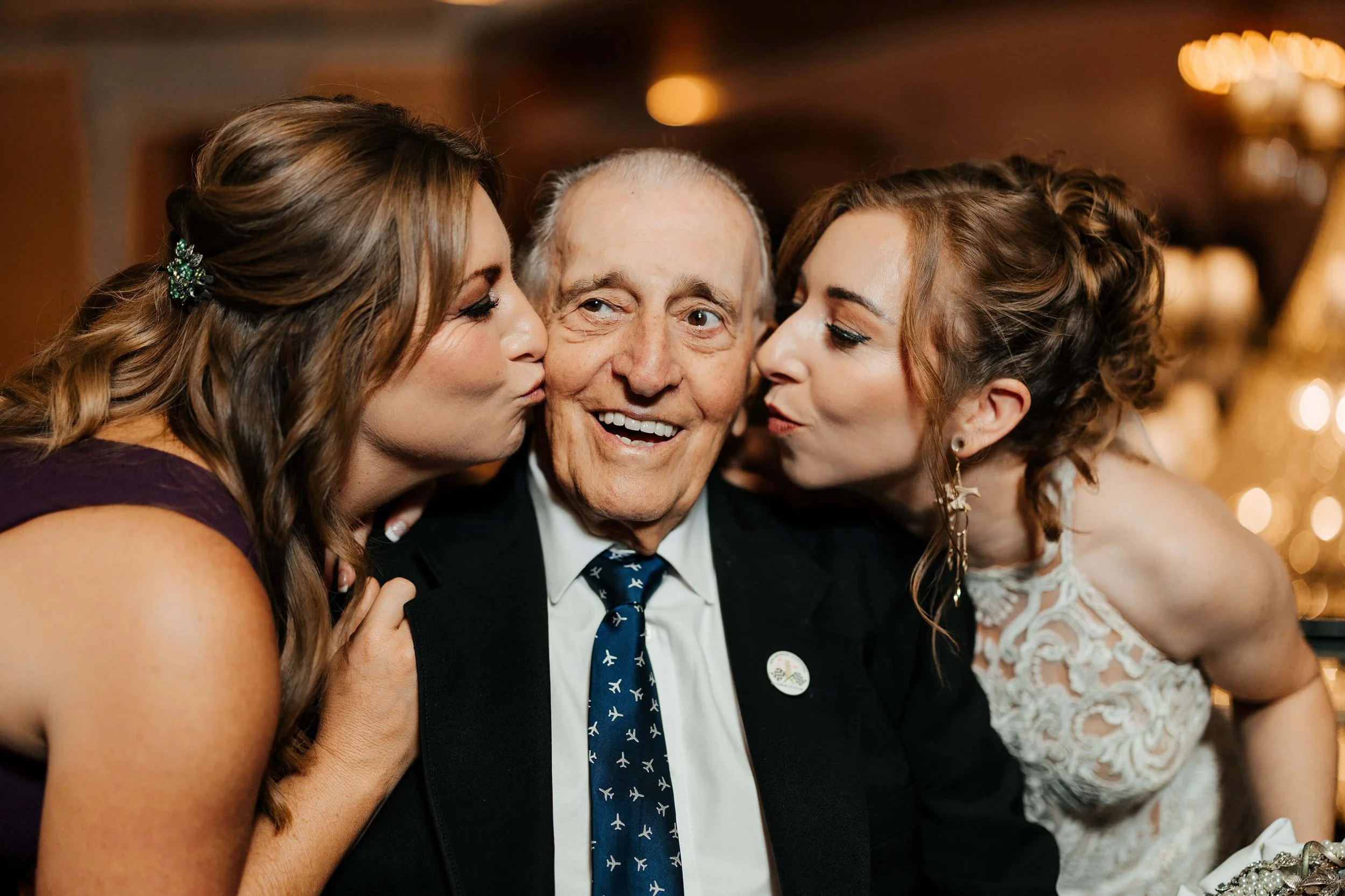 Amway Grand Plaza wedding photographer Grand Rapids candid reception moment bride kissing grandfather on cheeks, top Michigan wedding photography