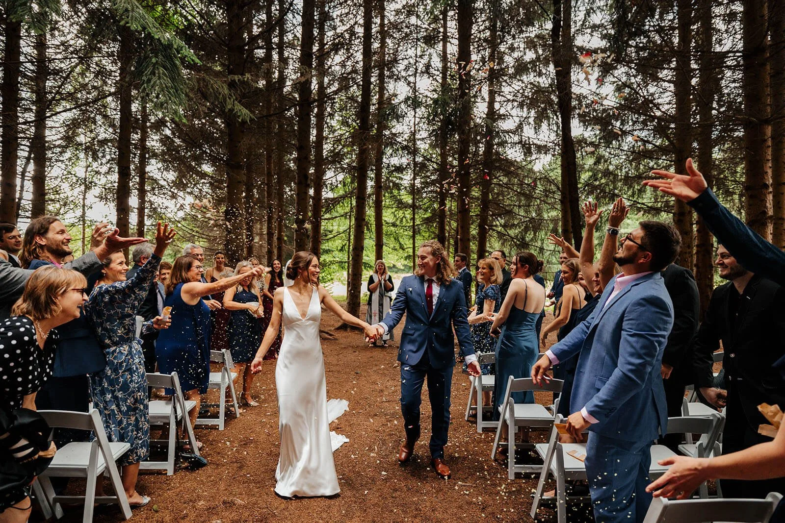 Pine Tree Barn wedding photographer Flushing Michigan bride and groom confetti recessional through pine forest ceremony aisle, top Michigan outdoor wedding photography