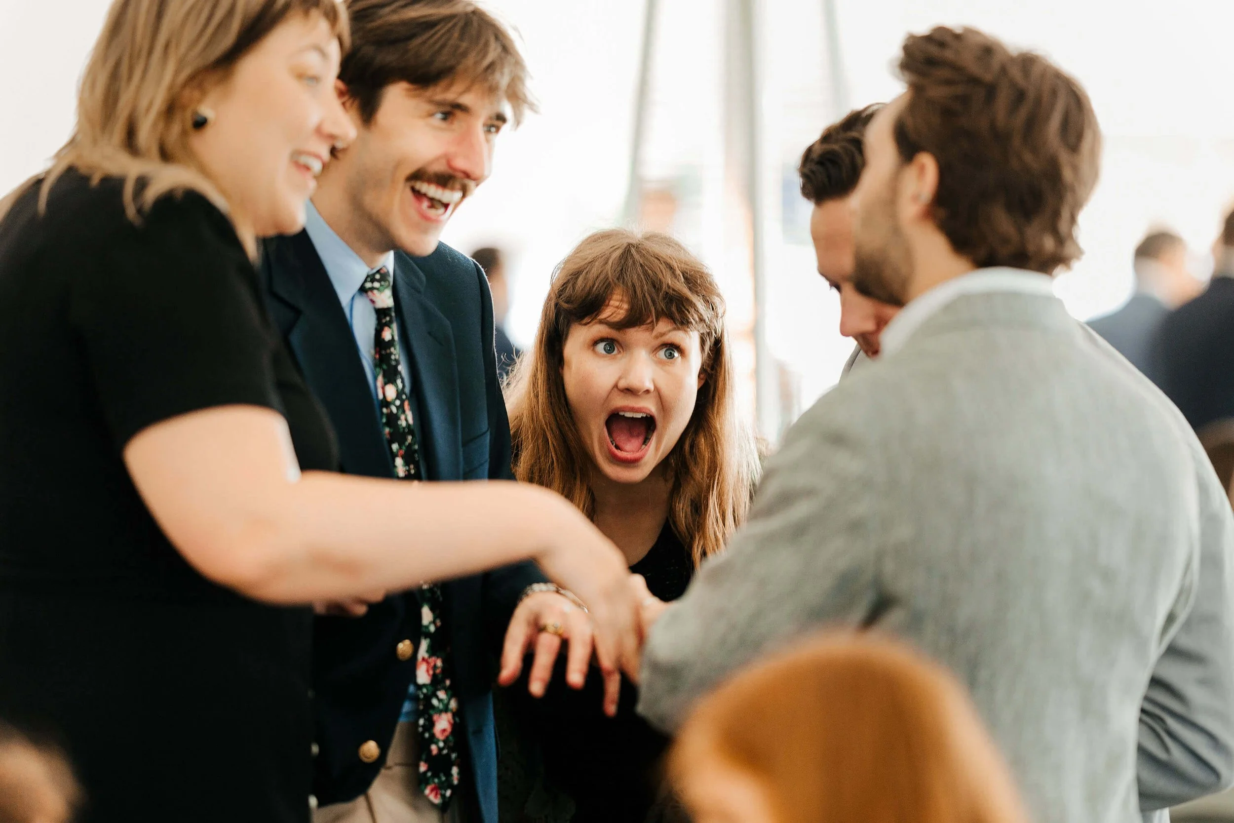 Jamesport Brewing Company wedding photographer Ludington Michigan candid guests laughing during cocktail hour, best West Michigan wedding photography