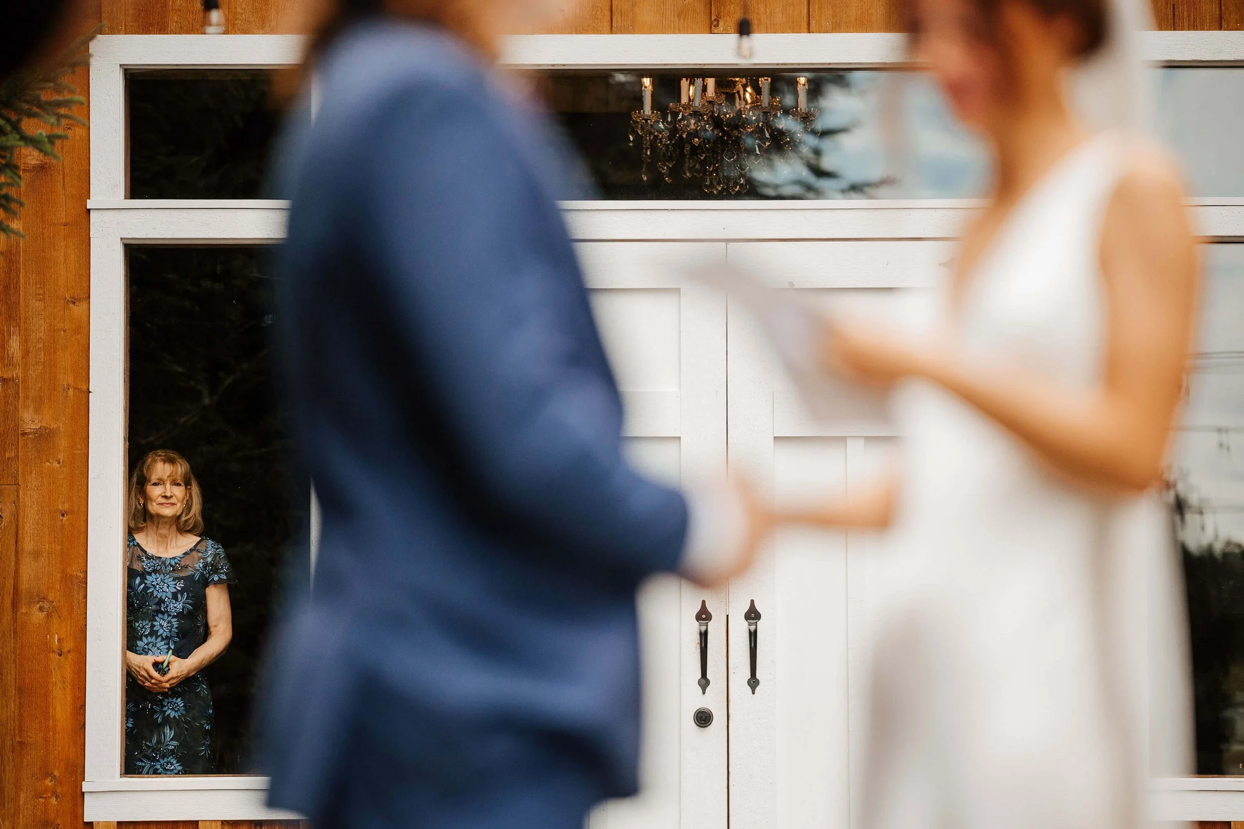 Pine Tree Barn wedding photographer Flushing Michigan candid mother watching vow exchange through window, documentary wedding photography Michigan