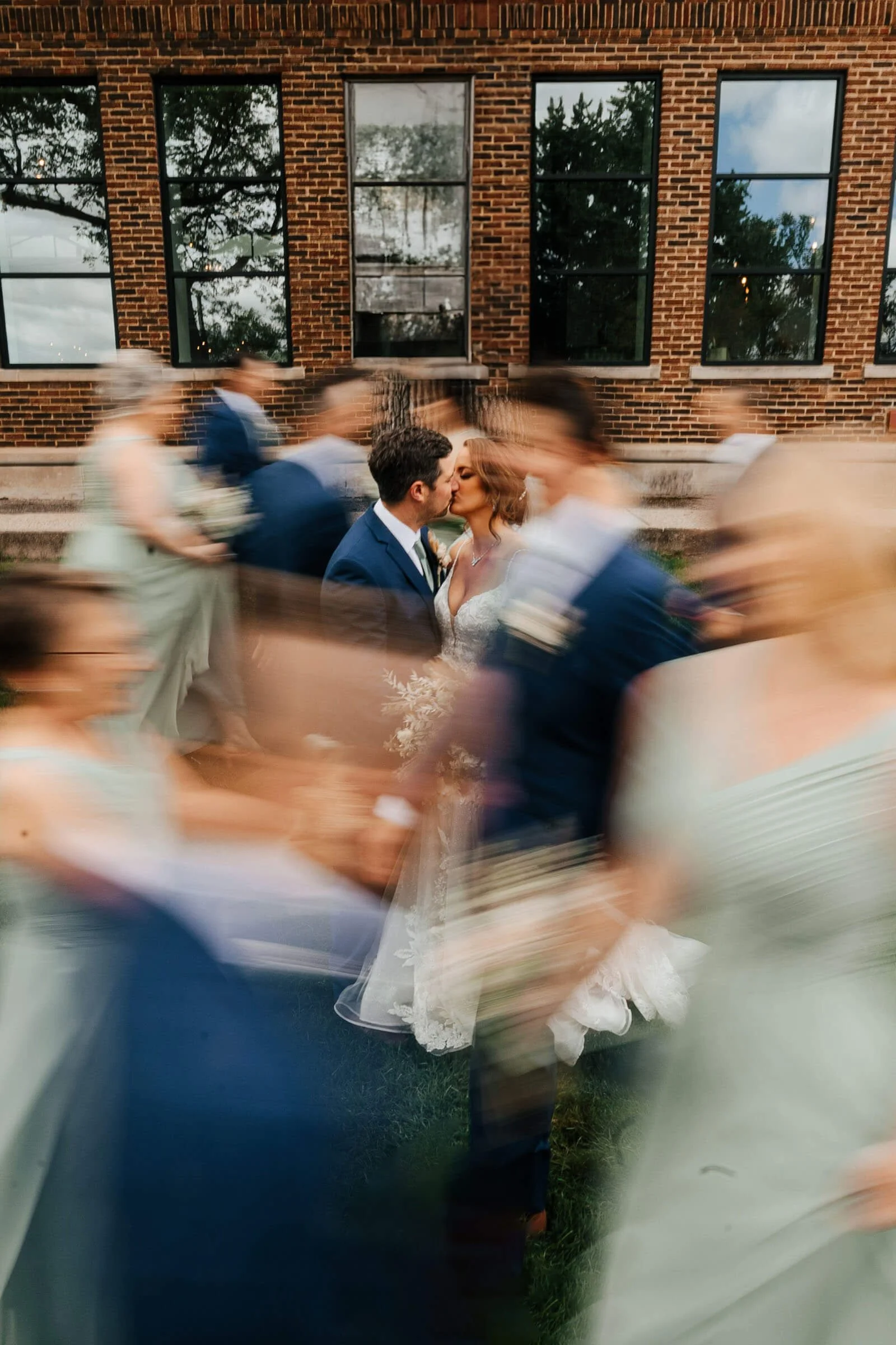 Leona Road wedding photographer Grand Rapids Michigan editorial bride and groom kissing with bridal party motion blur, best luxury documentary wedding photography