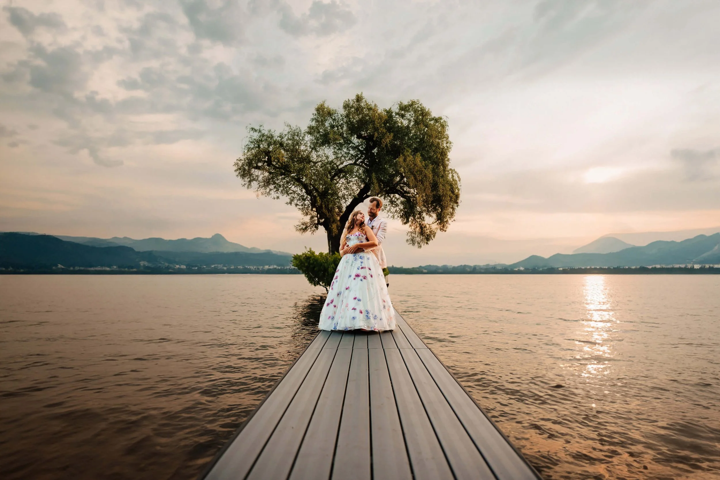 GAUPERphoto Flushing Michigan backyard wedding bride in colorful floral gown with groom on dock at lake sunset with willow tree and mountains, best documentary wedding photographer Michigan