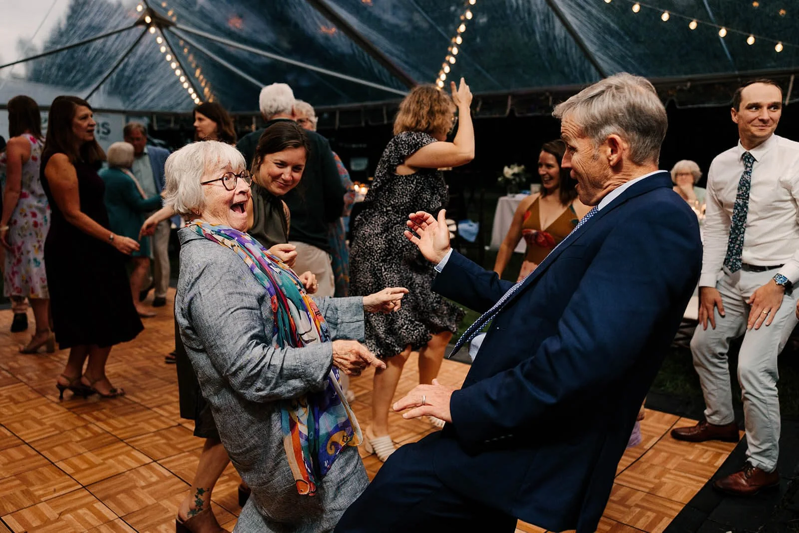 Ludington Michigan wedding photographer candid grandmother dancing at tented outdoor reception, top documentary wedding photography West Michigan