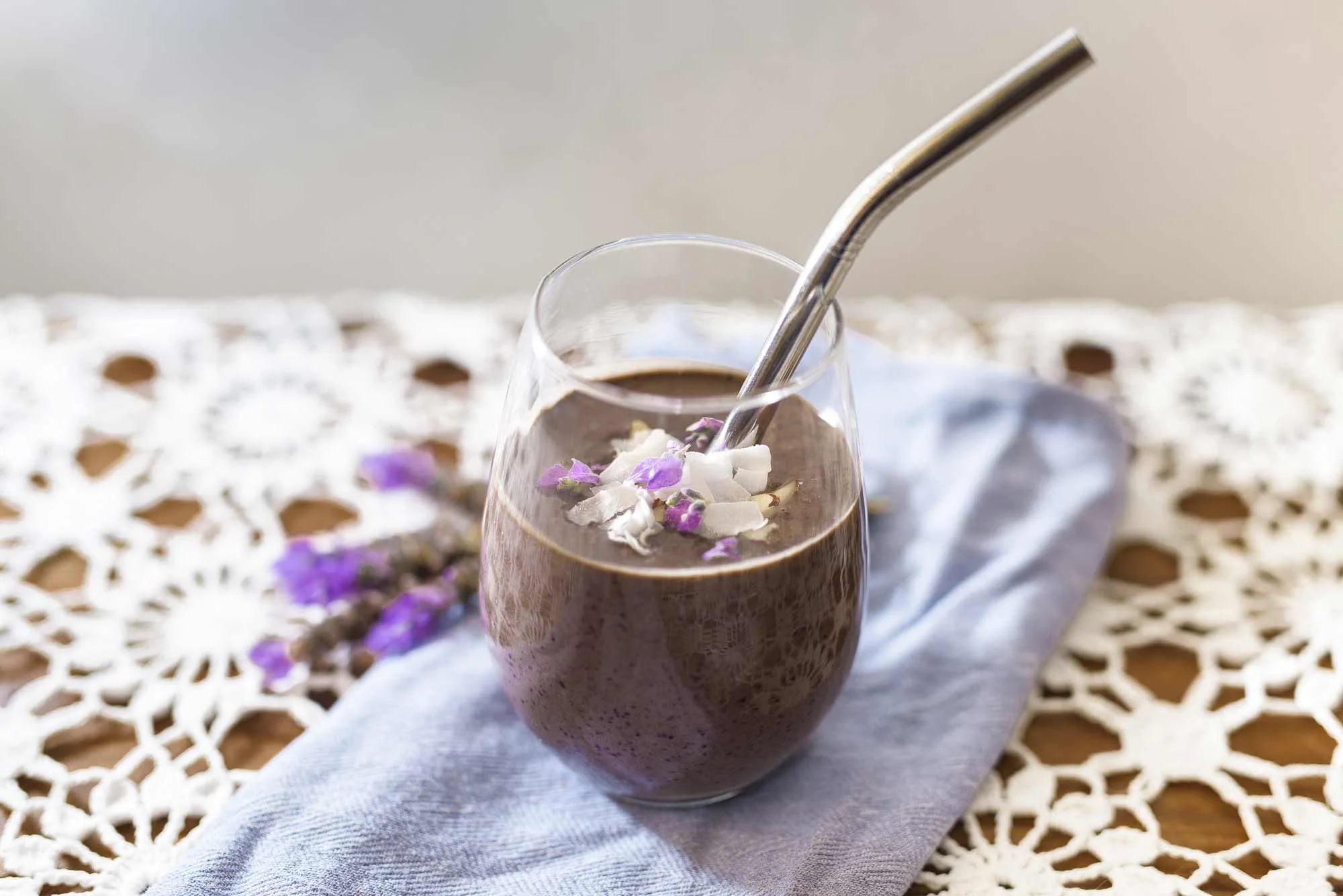 Blueberry cacao smoothie, so delicious. Garnished here with slithered almonds, dried coconut slithers and lavender petals.