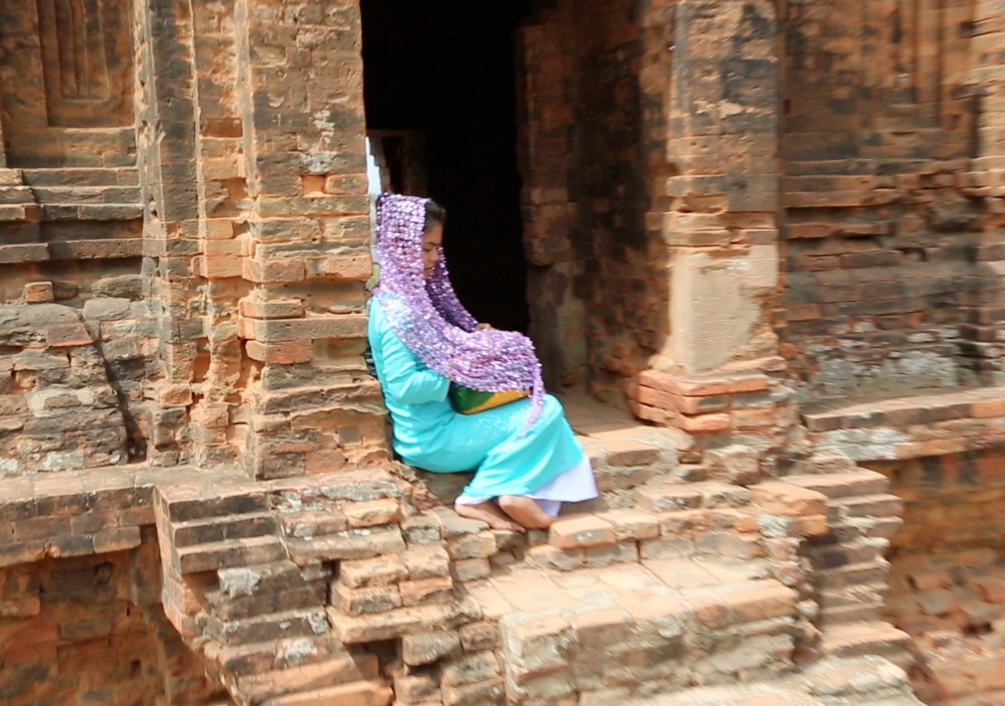 A Cham woman dresses up to pose for tourist pictures