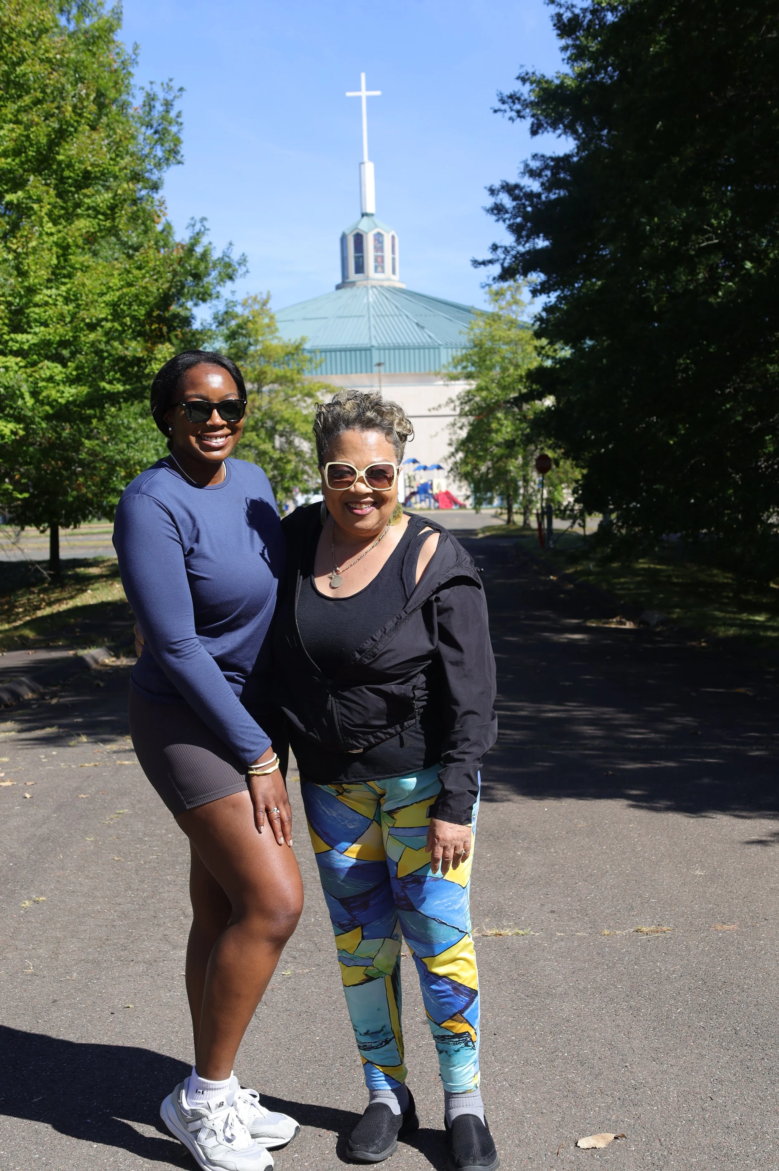 Two ladies pose during their walk between trees.