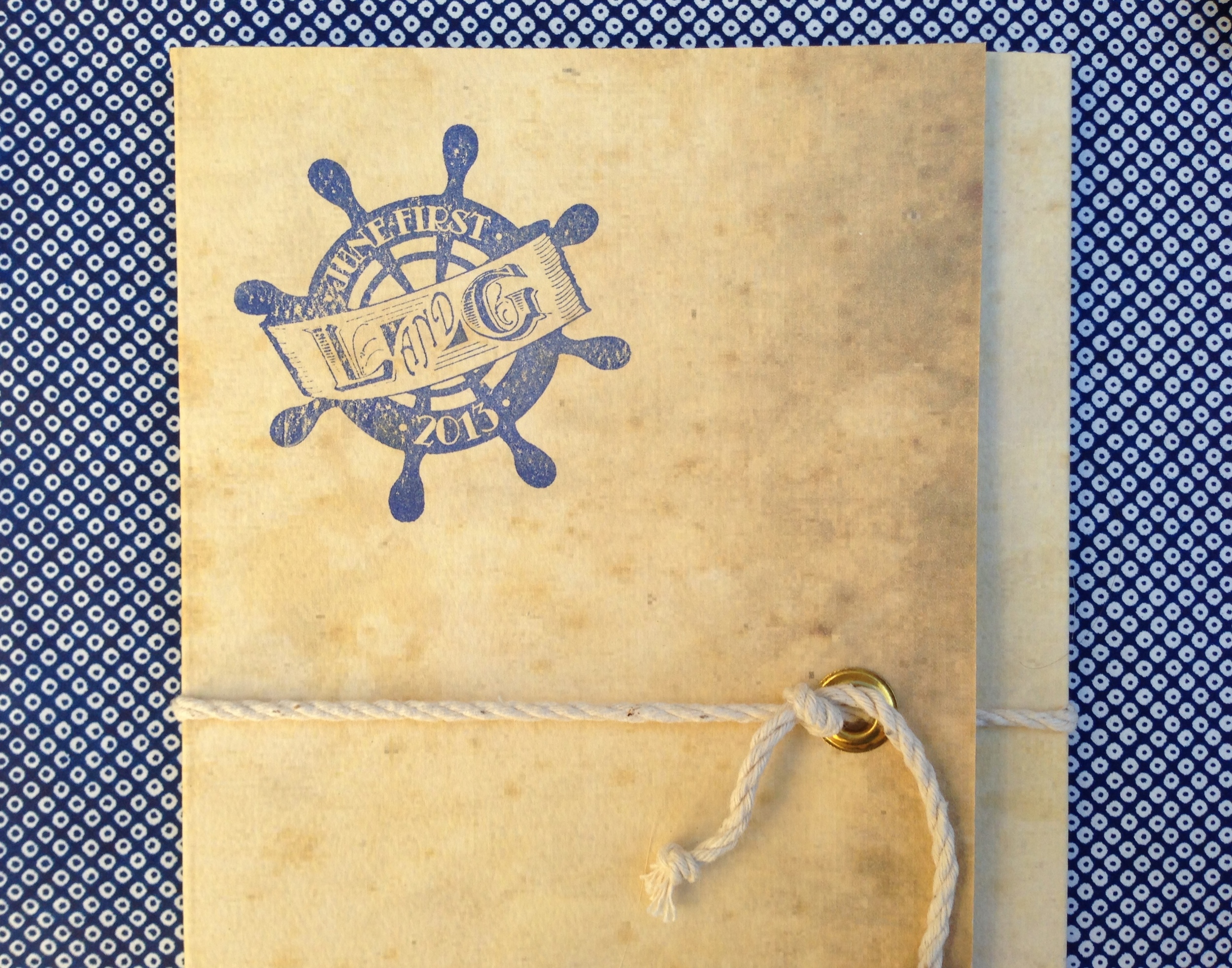  The outside of the folder was fitted with a brass grommet and tied with rope, then stamped with the couple's ship wheel logo.&nbsp; 