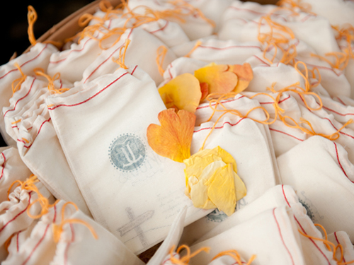  Tiny programs were nestled inside muslin sacks stamped with the couple's logo along side rose petals which were tossed as the newly married couple walked back down the aisle.&nbsp; 