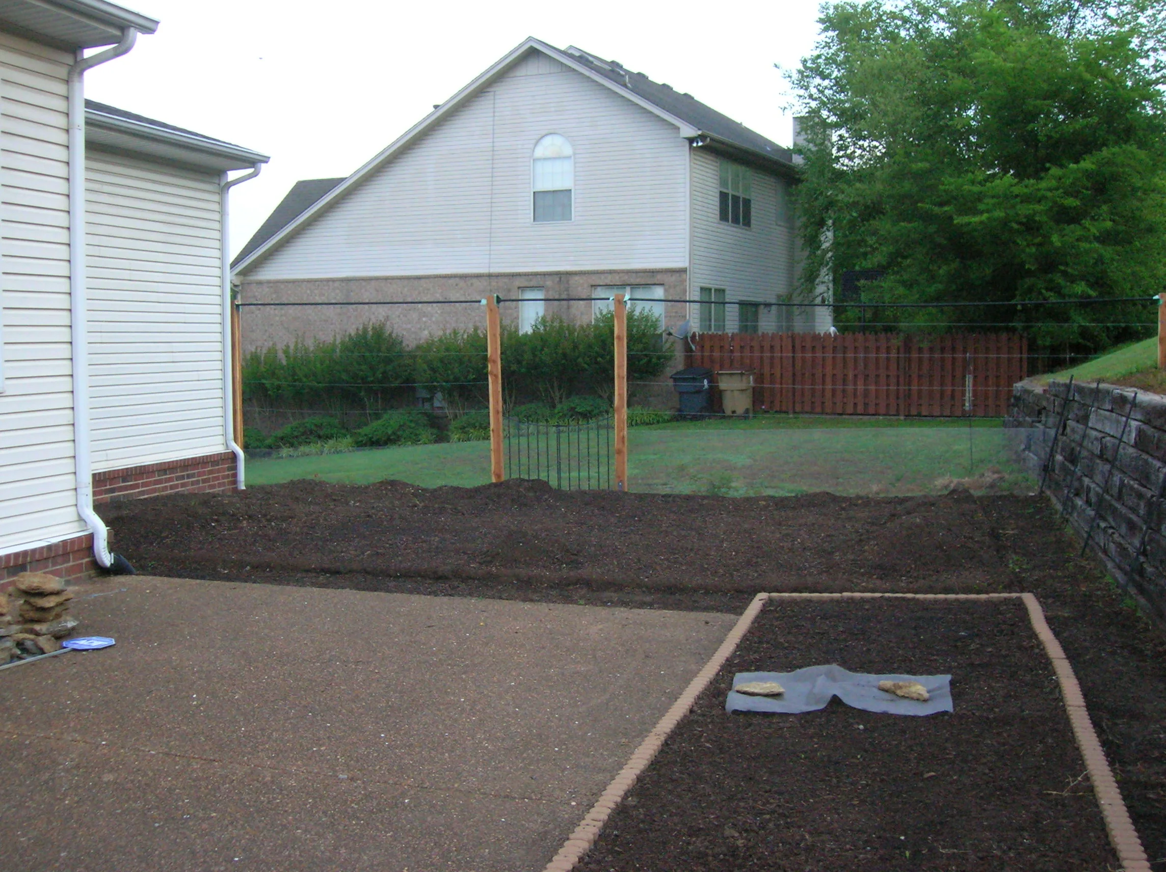 The soil has been delivered and spread, the arbors are in, and the 1st attempt at a retaining wall is set up. This is 6 weeks after the sod was cut.