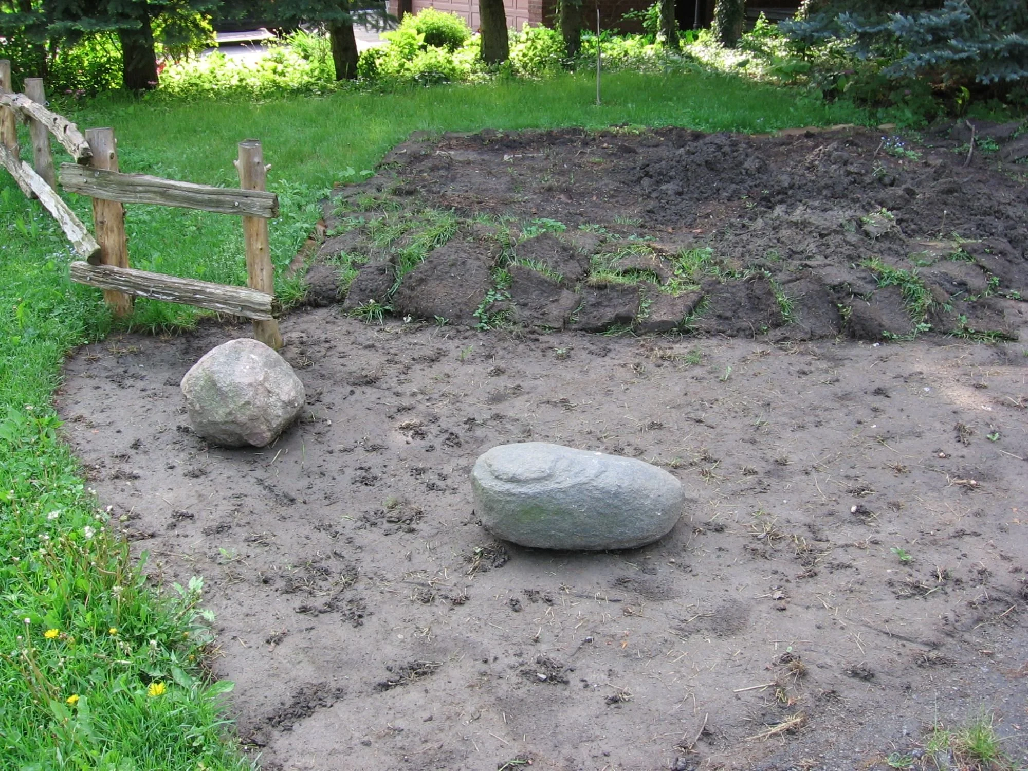 In the beginning: removing the front lawn, with some lawn removed, stacked upside-down turf, and some ornamental fencing and rocks in place.