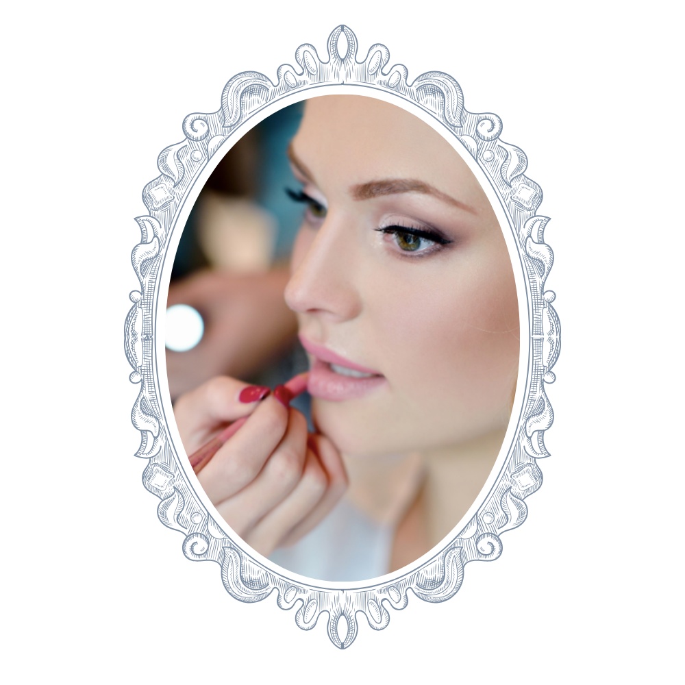 A woman is getting her makeup done, applying lipstick while looking into an ornate mirror.