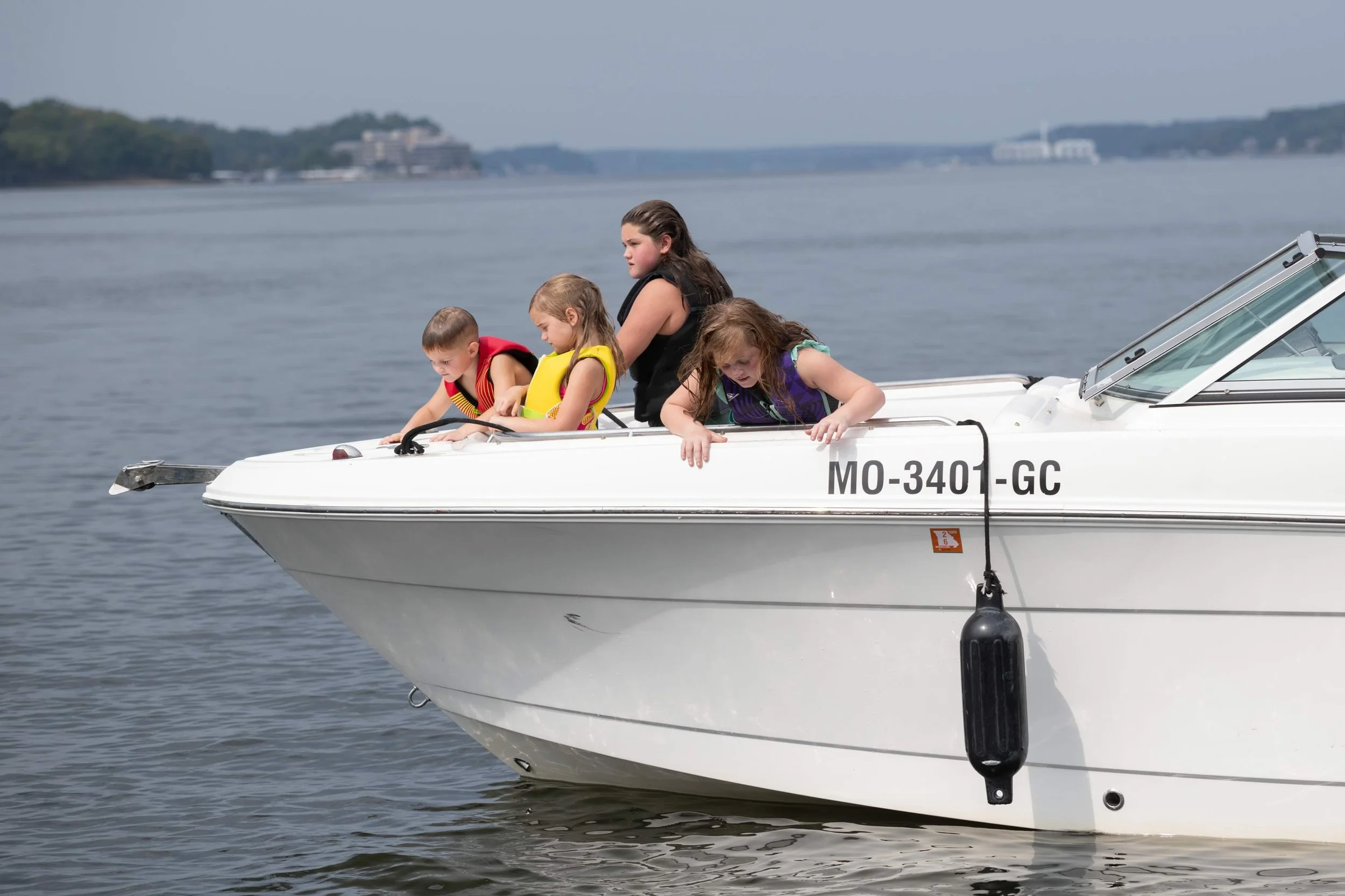kids on a boat with life jacket on the lake