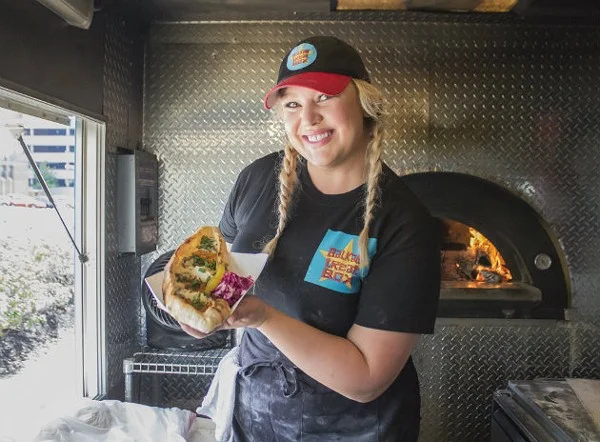 By Cheryl Baehr Loryn Nalic, chef and owner of Balkan Treat Box (314-667-9926; www.balkantreatbox.com), thanks her lucky stars that she learned how to cook at such a young age — it got her out of trouble with her parents. "I wasn't the best student, so when I got my report card, I would play restaurant for my parents," Nalic recalls. "I'd turn the whole house into a restaurant — cook dinner, put out flowers, dim the lights, everything. Food was always something I used to get myself out of situations." For Nalic, though, food wasn't just a way to get out of things. It was a way to get into them, too. The daughter of a busy working mother, Nalic would spend time with her mom in the kitchen, learning how to cook as they watched the Saturday morning PBS shows together. "She was a fantastic cook, and this was my way to be close to her," Nalic explains. "Anytime she was in the kitchen, I was right there with her." In addition to being a great home cook, Nalic's mother worked in restaurants. Naturally, her daughter picked up the love of the business, so when it came time for her first job, Nalic was hired on as a busser at the old Lemmons. A subsequent job at Yemanja Brazil gave her her first cooking break. "Yemanja was my first real taste of the professional kitchen. They really showed me around and taught me so much," says Nalic. "However, that's also where my first learned about the foods of different cultures. The chef was a joyous man who taught me about all of these foods that were different than what I grew up with." Though Nalic thrived in the kitchen, she took some time off from the business to raise her kids. When she was ready to go back to work, she found herself back on the line, this time doing pastries at Turvey's on the Green. That led to gigs with a few bakeries around town, as well as stints with Frazer's and the Del Pietro restaurant group. In search of a more family-friendly schedule, Nalic took a 9 to 5 food sales job — an opportunity that ironically set the course for her to return to the kitchen even as she'd been trying to get out of it. While calling on one of her accounts, she met Edo Nalic, the manager of south city's Taft Street Restaurant and Bar. "It was love at first sight," Nalic recalls. "Both of us say it was like a bolt of electric." Edo, a native of Bosnia, took Nalic to all of his haunts in the Bevo neighborhood and introduced her to Balkan food, a cuisine she fell in love just as quickly as she had with her husband. Nalic instantly knew that if she was going to open a restaurant, it would be this style of food. She learned as much as she could from Nalic's family, even going over to Bosnia and working in restaurants and home kitchens to soak up as much information as she could. Before she branching out on her own, however, Nalic took a job with the Pappy's Smokehouse as its catering and events manager a job that introduced her to some of the city's top chefs. As her idea for what would become the food truck Balkan Treat Box took shape, she sought training from the likes of Josh Galliano, Kevin Willmann and Qui Tran, who augmented her self-taught skills. In December 2016 she opened Balkan Treat Box as a roving purveyor of her beloved cuisine. Though she's not a native, Nalic insists that her food is every bit as authentic as if she'd been doing it her entire life. "I've watched Edo's family, and it's beautiful to see the way everything comes together," Nalic says. "The things they do have been passed down from generation to generation and they were starting to die out. That's why it was important for us to learn everything so we could preserve it." Nalic hopes to have a brick-and-mortar one day, but in the meantime, she's busy on the truck, stoking the wood-fired oven and making every last item from scratch. She took a break from the business to share her thoughts on the St. Louis culinary scene, how cooking is a lot like dancing and why two chefs are better than one. What is one thing people don’t know about you that you wish they did? I have been a dancer all my life and performed for the majority of my adult years as a professional and was a co-owner of a St. Louis dance troupe. We taught, performed and choreographed Turkish, Middle Eastern and Hawaiian dances. I still continue to teach on occasion to connect with that creative expression. While performing at restaurants and cultural institutions, I expanded my knowledge of food. I would always end up in discussions with people about what type of food they grew up on and how they cook it. Being a cook and dancing are very similar — the similarities are dedication, practice, creativity and and a level of vulnerability. They also require you to keep moving, learning and growing, which I need to stay stimulated. What daily ritual is non-negotiable for you? Between running the truck right now and our family life, it's easy to get preoccupied. I make sure to check in with my husband, daughter and son to keep ourselves grounded. I am working towards having those daily rituals again. I need them to feel balanced. If you could have any superpower, what would it be? The ability to to fly. Everyone needs a change in perspective for a little reality check. I also would travel everywhere! What is the most positive thing in food, wine or cocktails that you’ve noticed in St. Louis over the past year? Growth. I love that there are so many choices and new places opening. If only we could have more culinary professionals to staff them to keep it growing. I also love seeing St. Louis (Seoul Taco, Pastaria) repping in other cities. That feels good. What is something missing in the local food, wine or cocktail scene that you’d like to see? I'd like to see more food stalls or a place for them around St. Louis where there is prominent foot traffic. Who is your St. Louis food crush? Oh man, I'm going to take this in a different direction. I have three solid duo crushes in St. Louis. I want to be a little like all of them. One duo in particular that I hope makes a comeback someday is Josh Squared: Galliano and Poletti. Theirs is still some of the best food I can remember here. Josh Galliano has mentored some of the best chefs in St. Louis. He lives and breathes his work and is extremely helpful. I respect that. Another pair is Qui Tran and Marie-Anne Velasco. Not only are they extremely knowledgeable and savvy, they remind me that we can be professional and still have fun. These two are seriously local celebrities to me. There is also nothing Marie-Anne doesn't know, culinary-wise, and there is nothing Qui won't do to help someone out. Finally, there's Ermina and Senada Grbic. Wow. These women. They are the hardest working ladies in the business. They have grown a little local empire, and their talent and ability to make everyone feel like family is admirable. Some of my favorite foods come out of their kitchens. And you always listen to everything Mama Grbic says — well I do! Who’s the one person to watch right now in the St. Louis dining scene? It’s another team for me, because one person can't do it alone — Kevin Willmann's line over at Farmhaus: Jake Sciales, Michael Frank, and Traviss Smelser. It's simple, yet creative, food done the right way that tastes damn good. The four of them make up a dream team. Farmhaus is on fire! Which ingredient is most representative of your personality? I’m a big personality, so I will say cilantro. You either can't get enough — or I taste like soap. If you weren’t working in the restaurant business, what would you be doing? Some sort of starving artist in the entertainment business. You know, like the restaurant business — ha! Name an ingredient never allowed in your kitchen. None. I am very inclusive and see that there is a place for everything. What is your after-work hangout? Lemmons by Grbic and my backyard. What’s your food or beverage guilty pleasure? Anything sparkling and anything sweet. What would be your last meal on earth? Anything my mom, Linda Pucci, cooks!