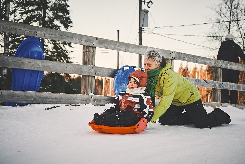 grandmother pushing sled and kid