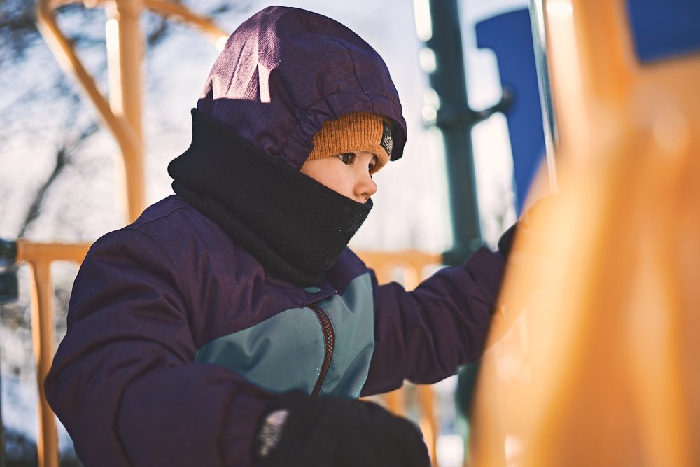 young girl playing on a park module in winter suit