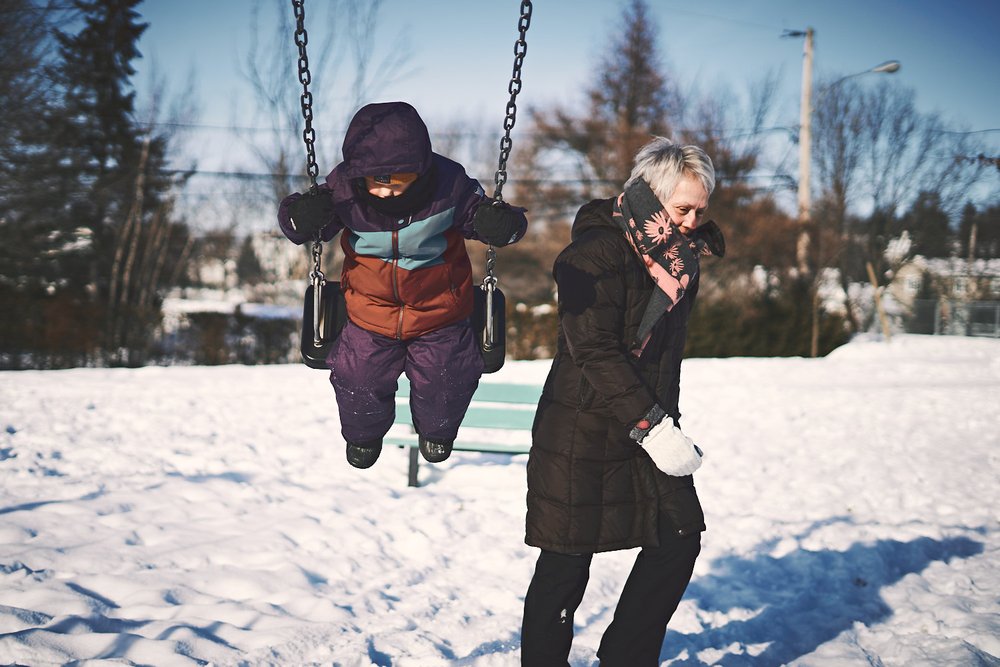 grandmother and young girl on a swing in winter