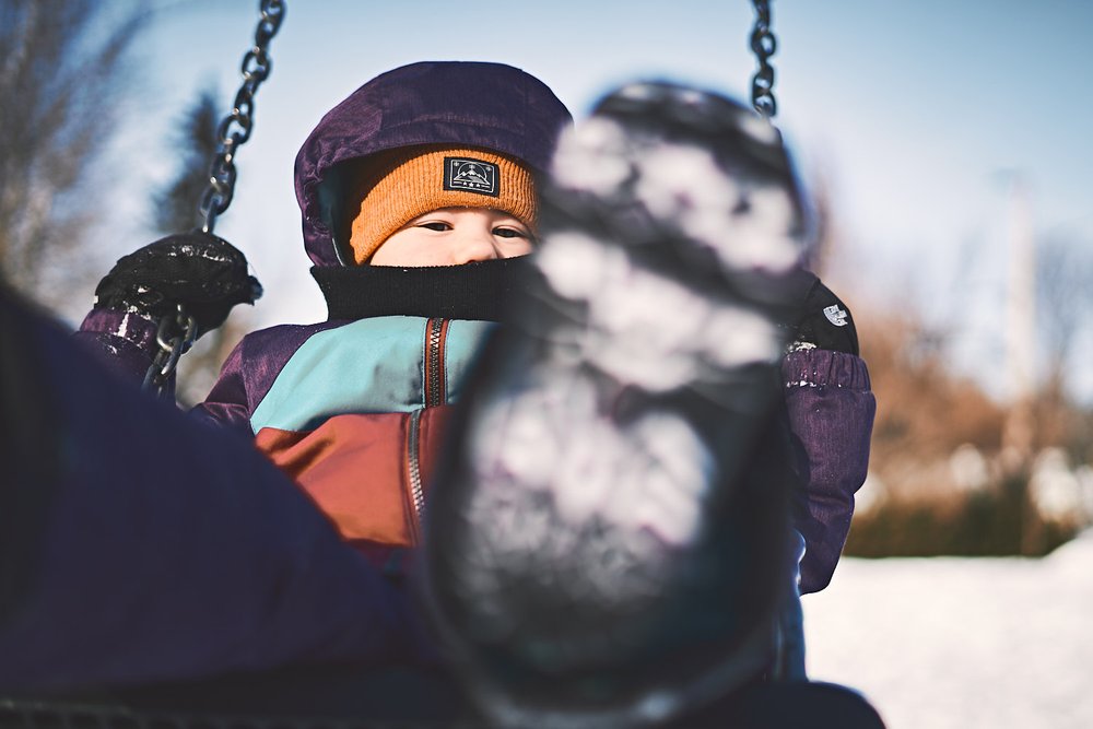 young girl on a swing in winter looking into camera