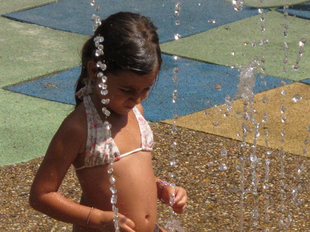 A young girl frolicking around during a summer afternoon in Washington Square Park.