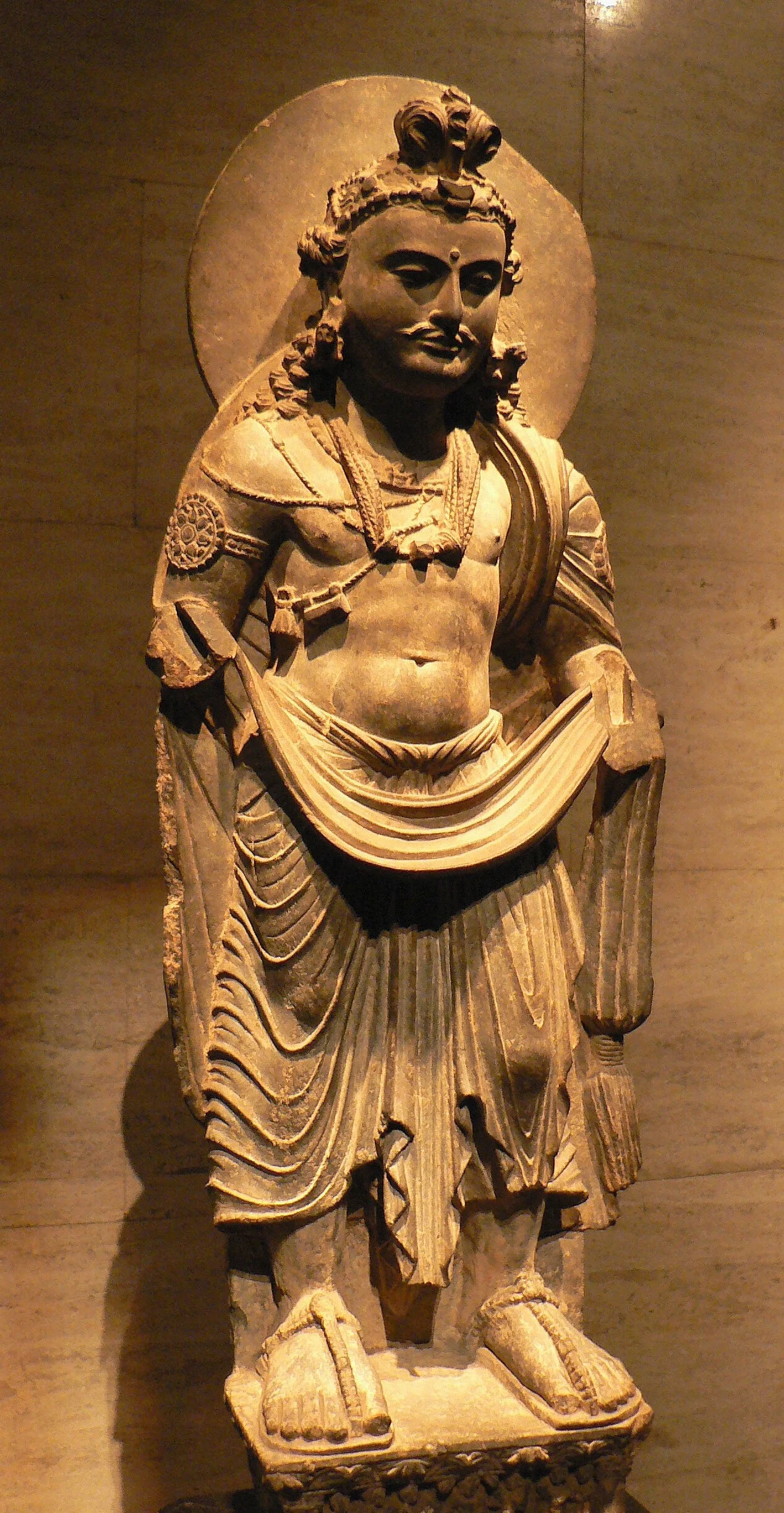    Sur cette représentation du Bouddha du futur, Maitreya, le chignon reste parfaitement identifiable et il est doté de bien belles moustaches (statue conservée au Metropolitan Museum of Art, New York et &nbsp;présentée dans l’exposition de Tokyo).   