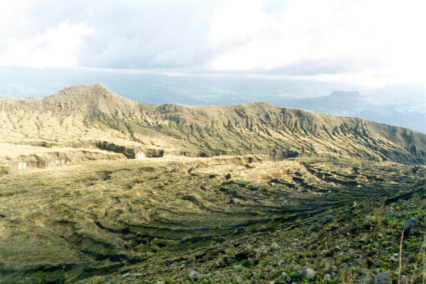   A l’approche du cratère, la zone intermédiaire entre les crête démantelées de l’ancienne caldeira et les rebords du cratère actuel constitue un lieu de concentration des eaux de pluie. Le ruissellement révèle les festons des écoulements des laves hors du cratère.  