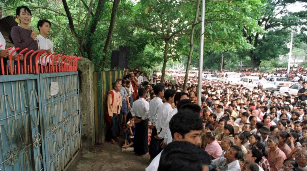  Aung San Suu Kyi, entourée des leaders de la NLD (National League for Democracy) s’adresse aux militants depuis la maison où elle est en résidence surveillée (été 1996). La plupart des manifestant venus l’écouter seront arrêtés et emprisonnés. 