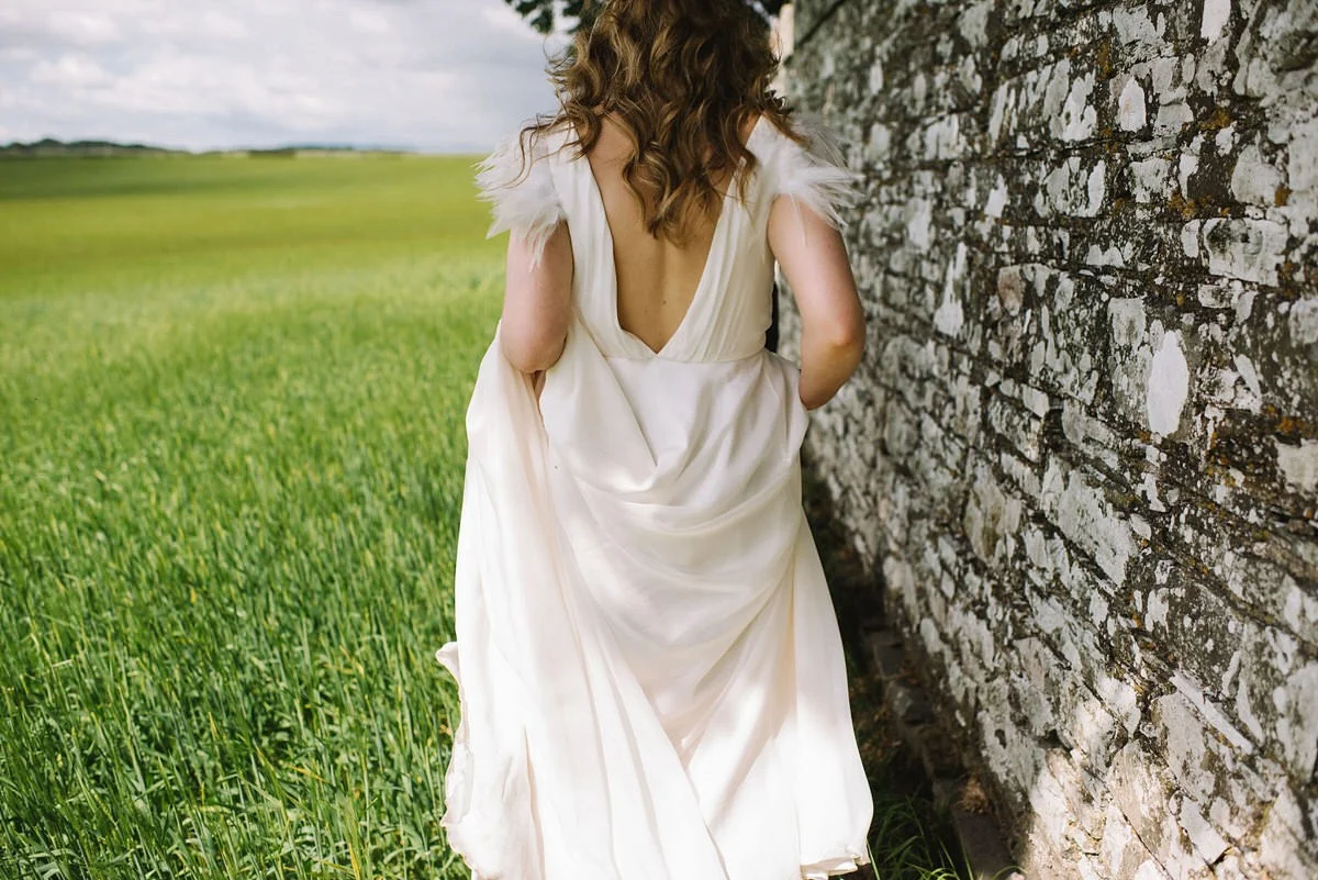 Beautiful Saskia wears a wedding dress by halfpenny London featuring a stunning V back and feather sleeves
