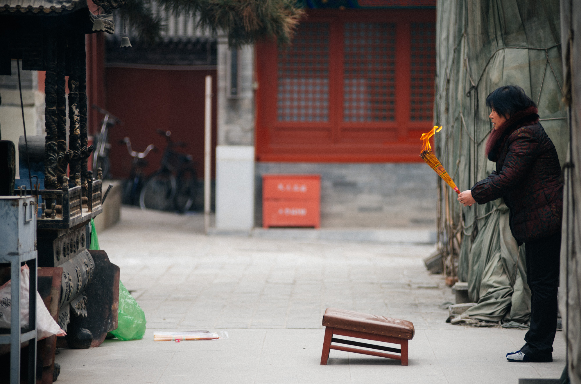 After lighting the incense, a woman bows facing the pagoda and prays before kneeling and bowing several more times, then heads to walk around the building.