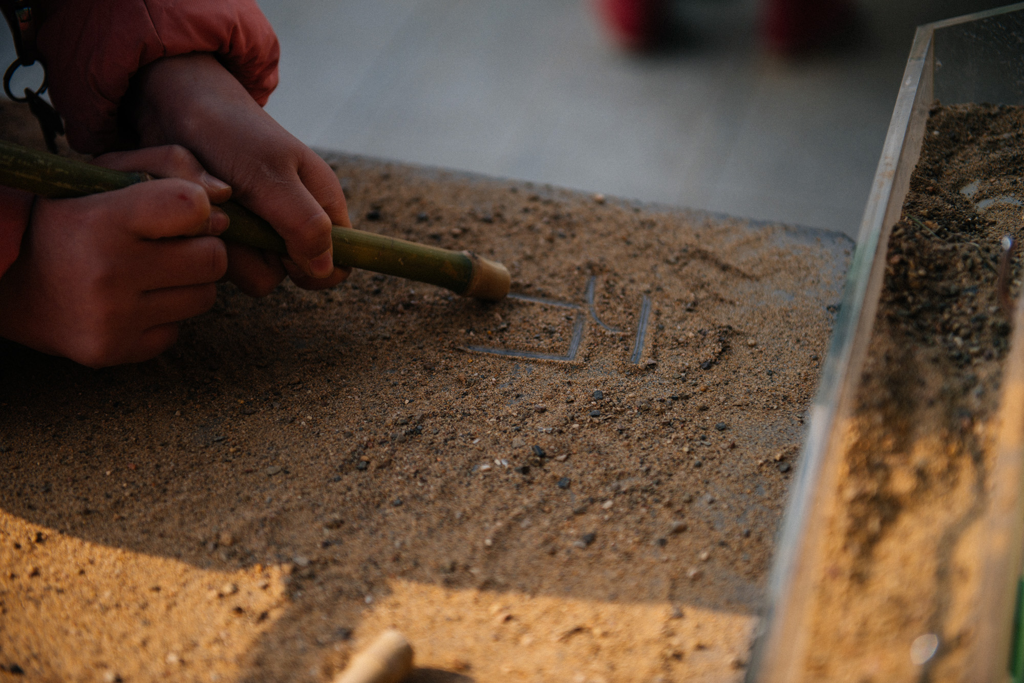 Behind the temple there is a museum with activities for children. Here a child inscribes in sand the word stone (石 ).
