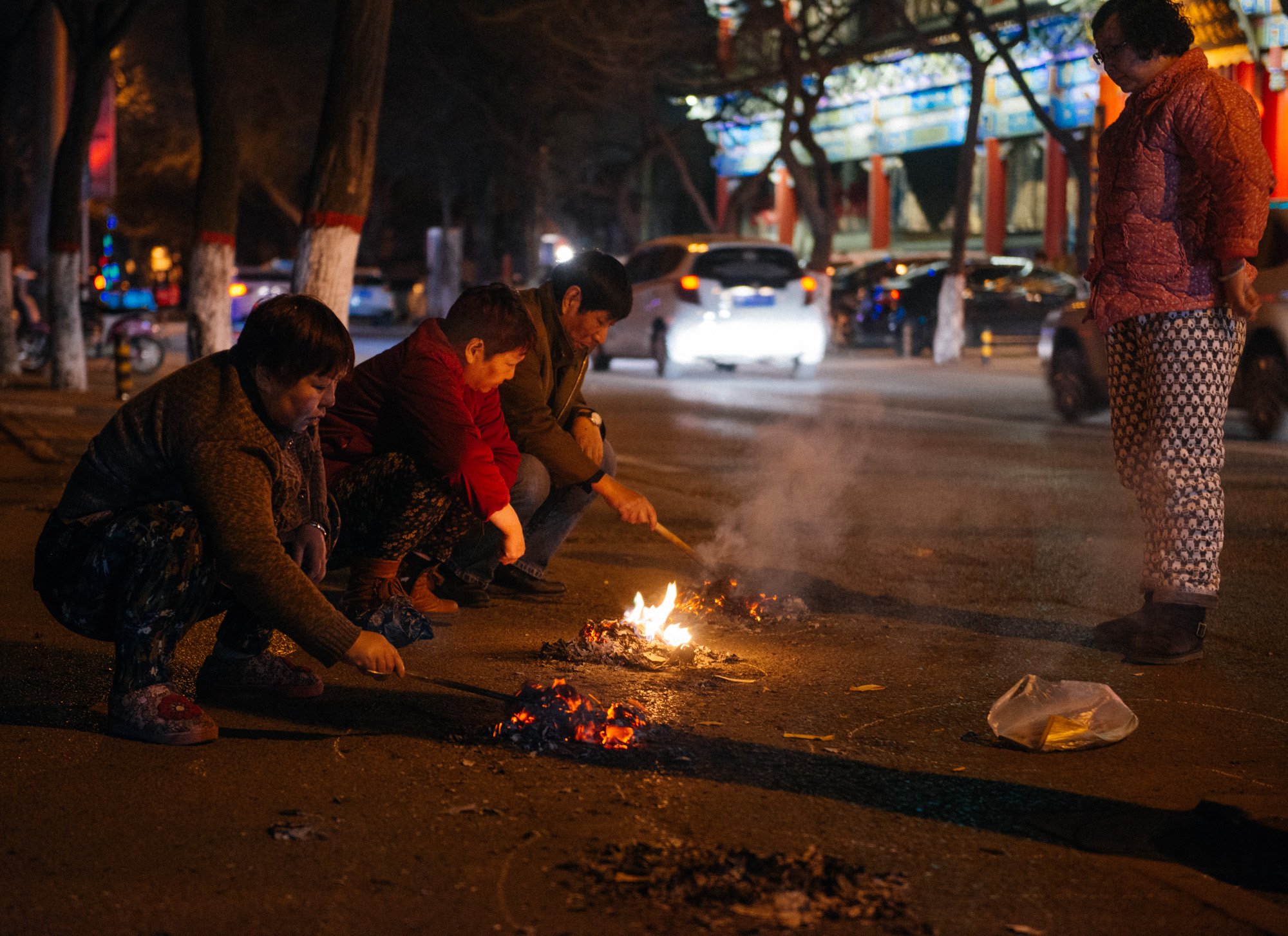 On New Year's Eve, it's a tradition to burn fake money in honor of dead loved ones. Basically, instead of burning real money, you trade it for a larger volume of fake money, just so it lasts longer. As you can see on the ground, they draw a circle with an opening on one side and put the paper to burn in there. I noticed that no opening was ever facing another. I'm sure there is a meaning to it.