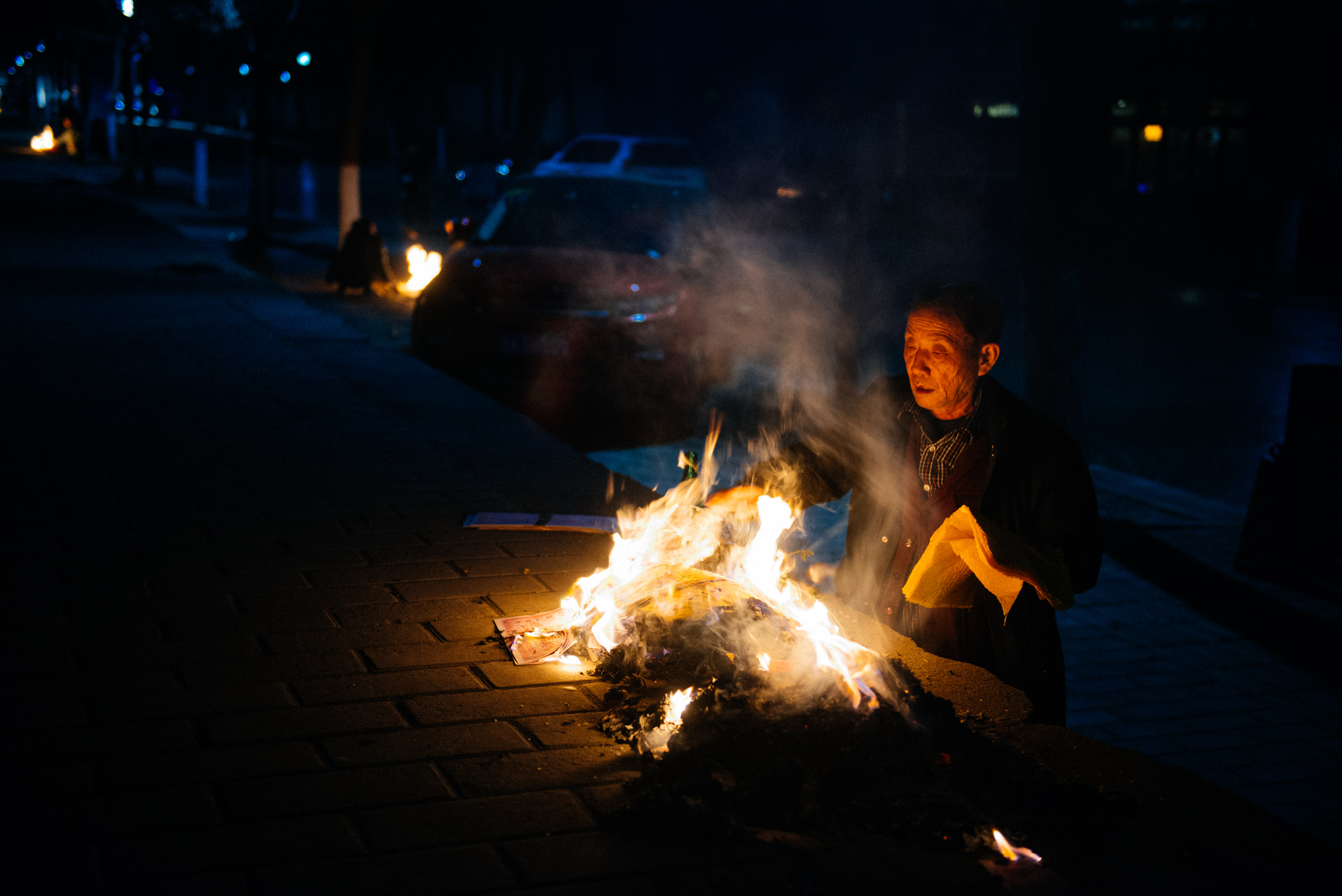 Right at the bottom of the east side of the old city walls, an old man burns tons of paper.