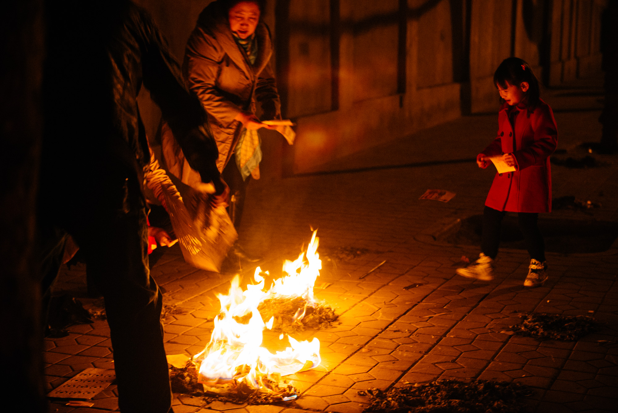 This little girl was very scared of the fire. Her grandmother would tell her to throw the money in but at first she wouldn't. After a few tears, she gathered the courage.