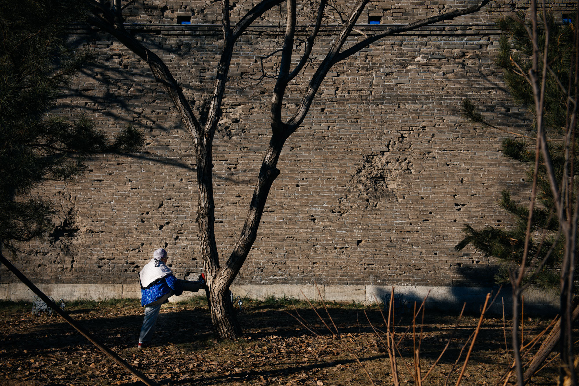 Old lady stretches for her morning exercise outside the Wanping fortress. Battle marks are clearly seen on the wall.
