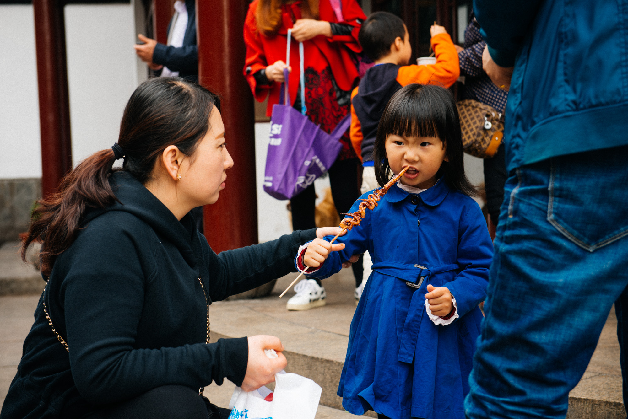 Little girl struggles to eat a squid tentacle. Street food is one of the main attractions in Qibao.