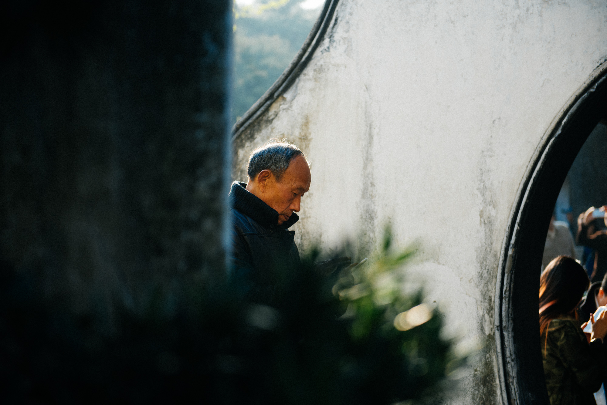 Man checks his phone beside the famous round arch of the garden. You can also see several others checking their phones through the doorway.