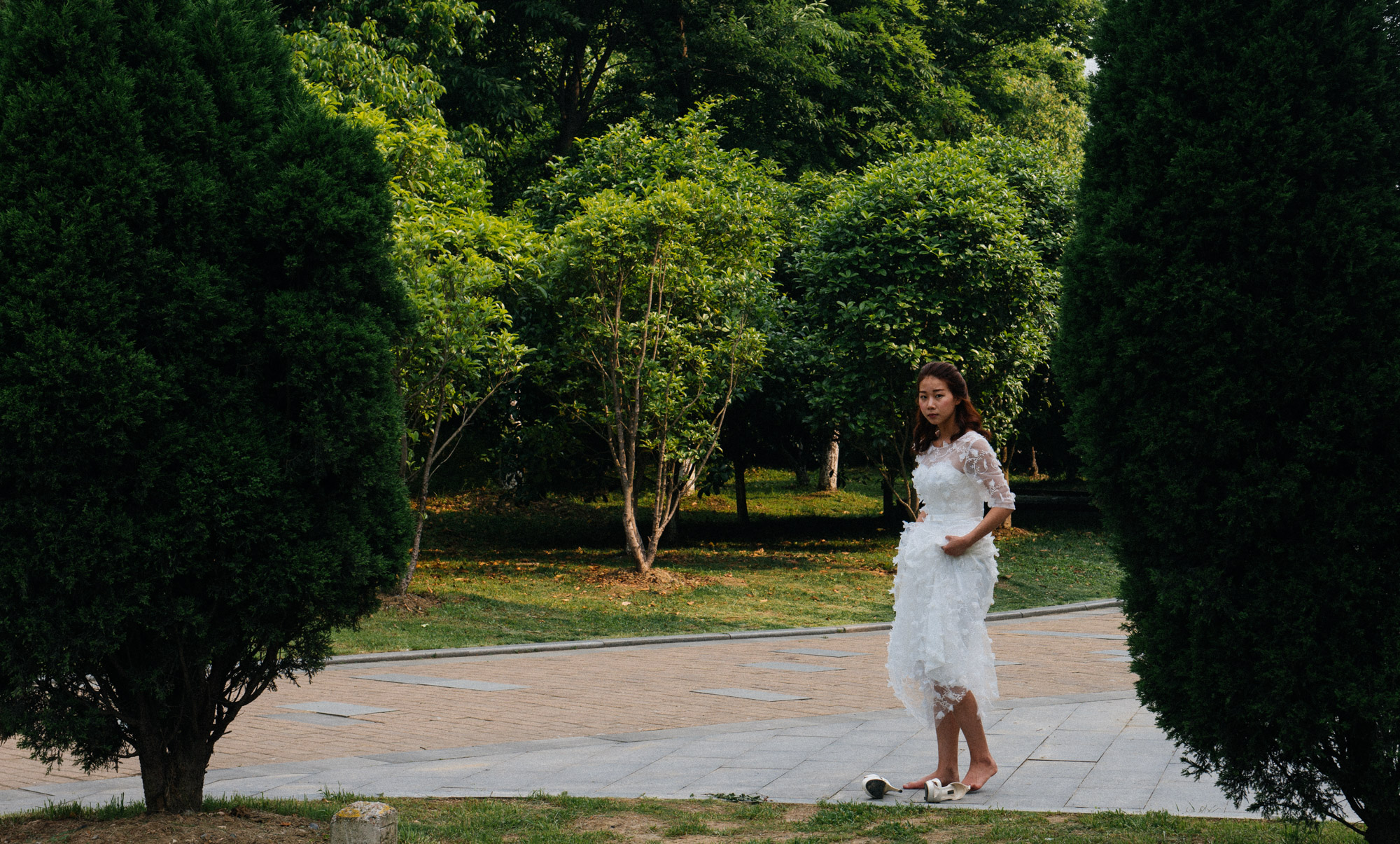 As I mentioned before, these photographic session can last hours or even days. It can be extremely tiring to walk in heels all day while someone keeps telling you to stand straight and smile. This bride takes a rest in a park while the photographer prepares for the shoot.