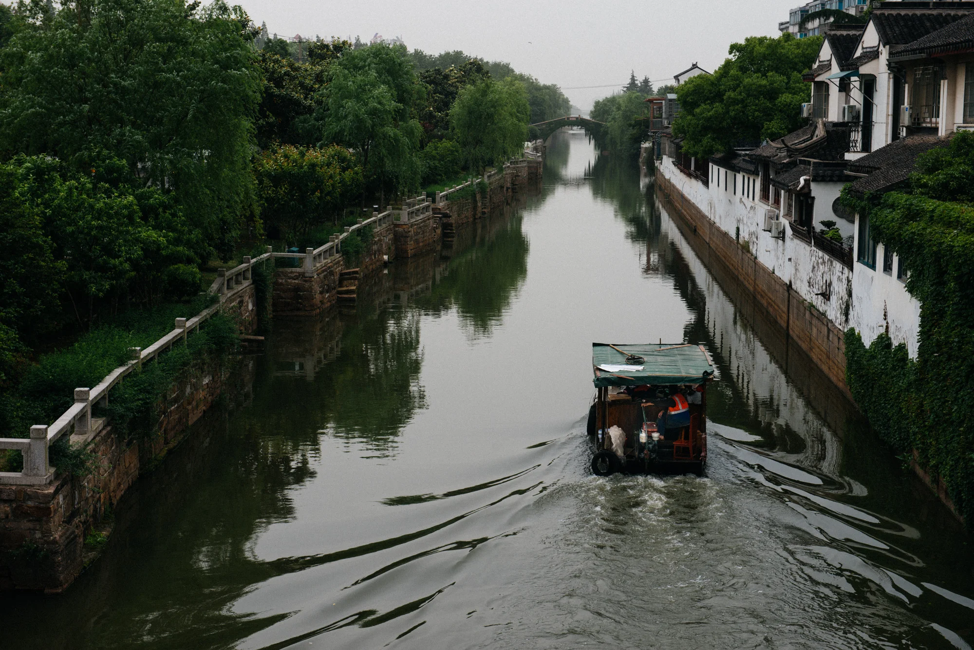 A boat used for cleaning the water passes through a canal close to the Lingering Garden . 
