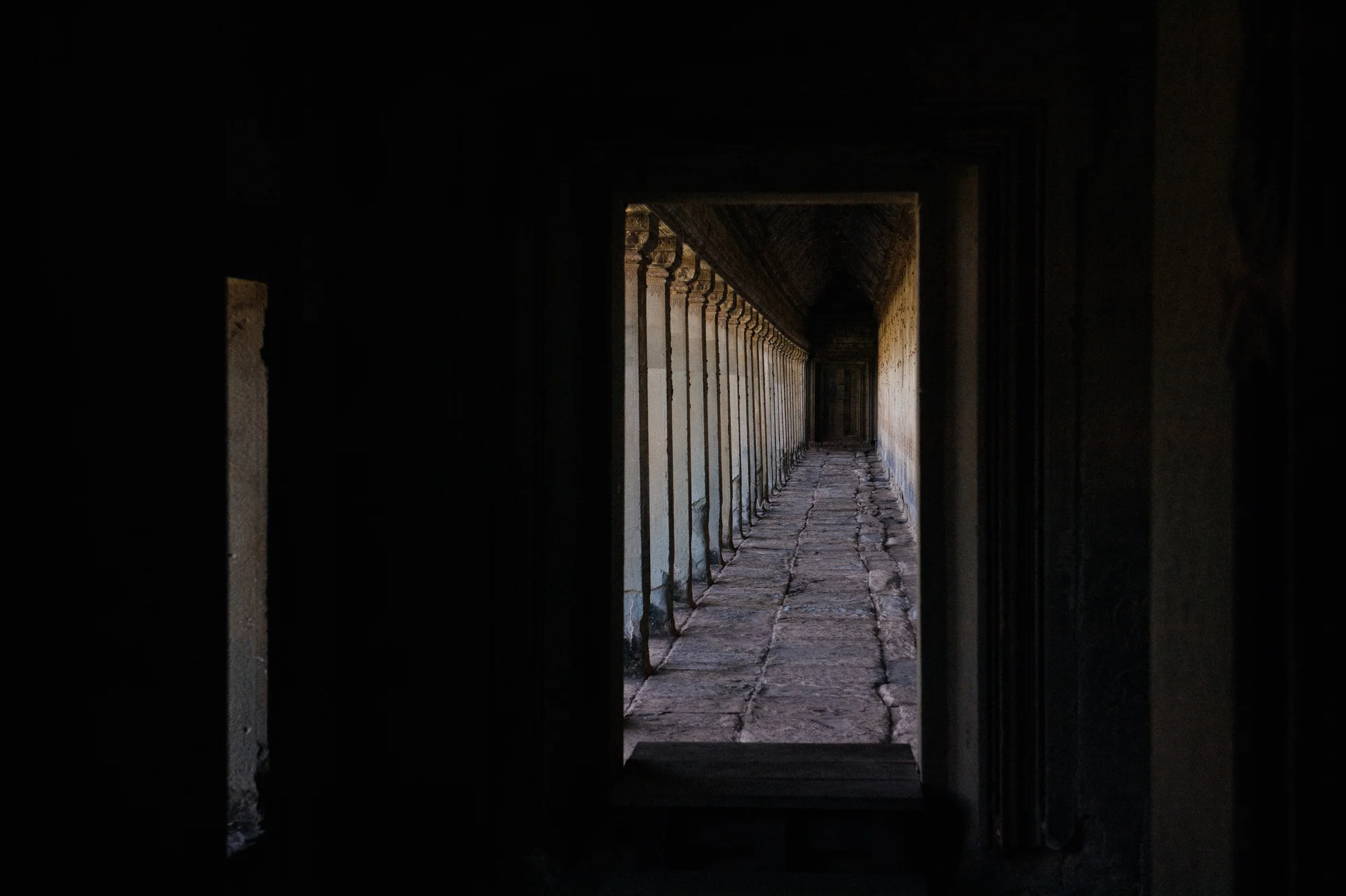 Angkor Wat has a huge corridor surrounding the temple like a frame. Along the walls are inscriptions of great battles of the Khmer empire. View from inside the Gallery of 1000 Buddhas into the Battle of Lanka corridor.