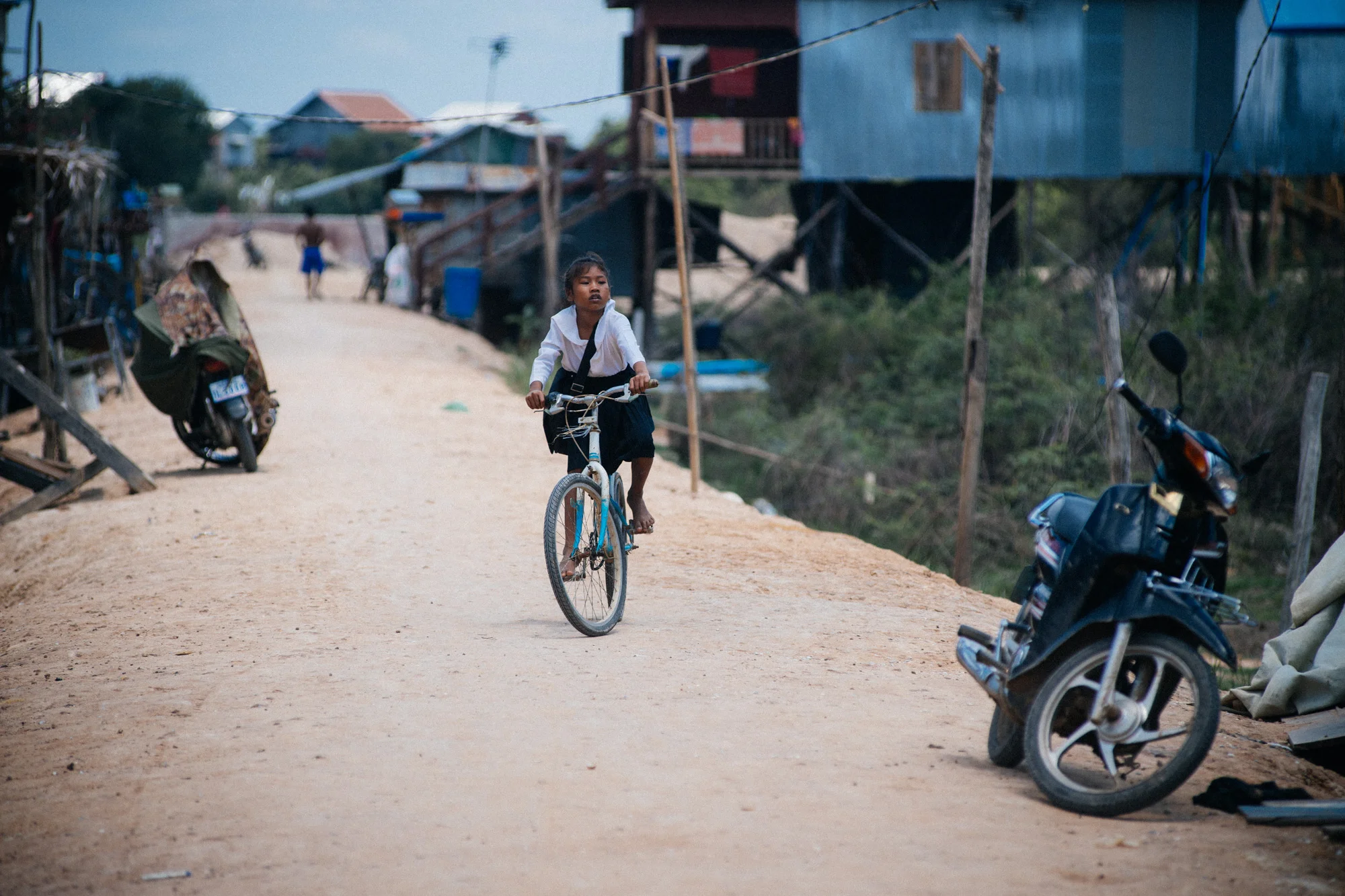 Girl barefoot in her school uniform rides to class after her lunch break. They travel several kilometers sometimes just to get an education.