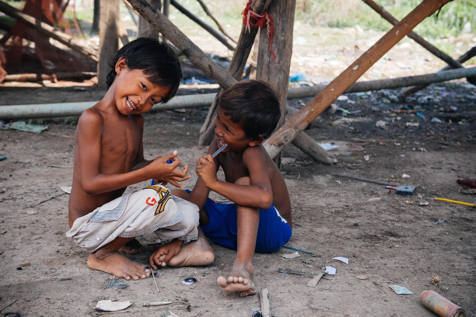 Boys in a village on the banks of the Siem Reap play with a broken pen and a plastic gun that shoots rubber bands.