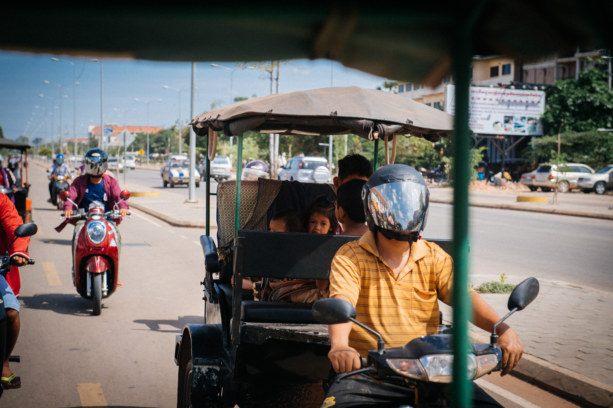 Children accompany their father on a tuk-tuk ride. These adapted motorcycles are an essential mean of transportation in Southeast Asian countries, cheaper than cars and more convenient than bikes.