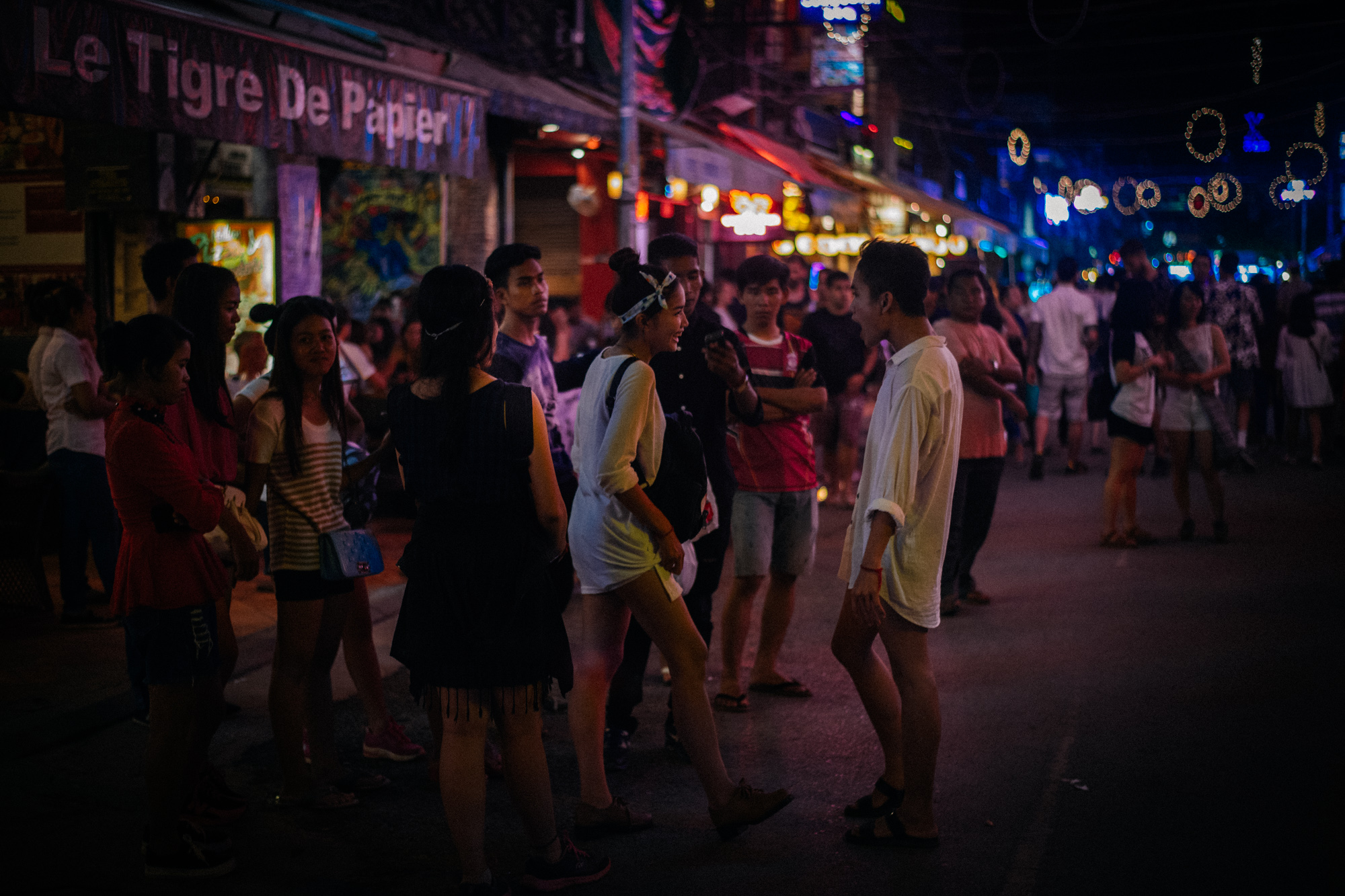Group of Cambodians chats in front of restaurants on bar street.