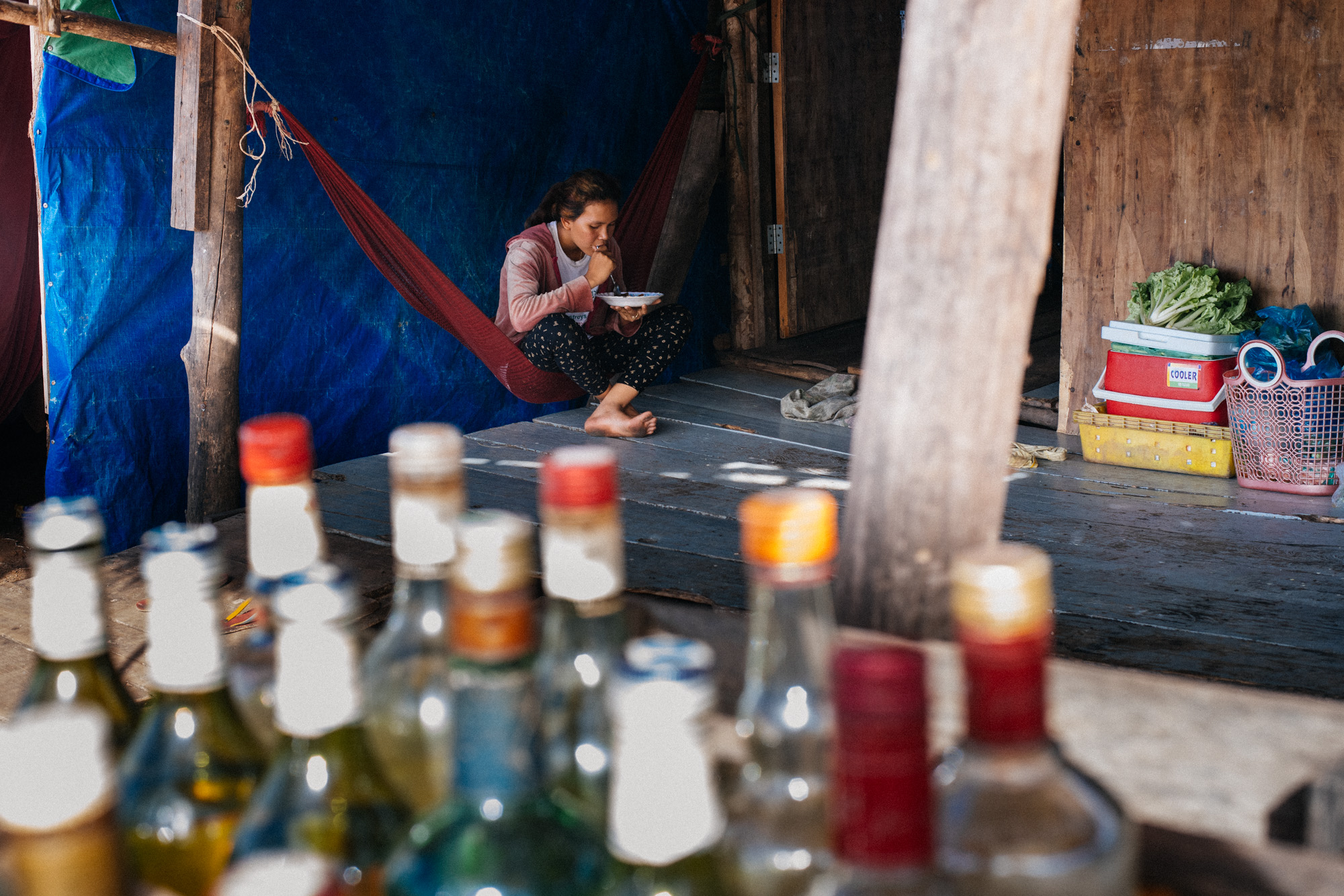 Woman has lunch on a hammock at noon in the village on the roadside, only a few meters from the beach.